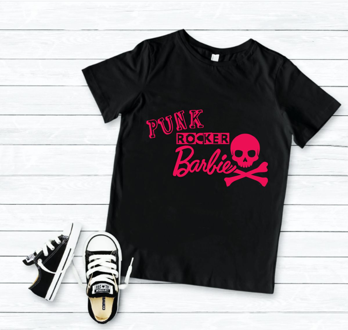 Camiseta preta com estampa rosa Punk Rocker Barbie e caveira, com ténis preto e branco ao lado sobre chão de madeira branca
