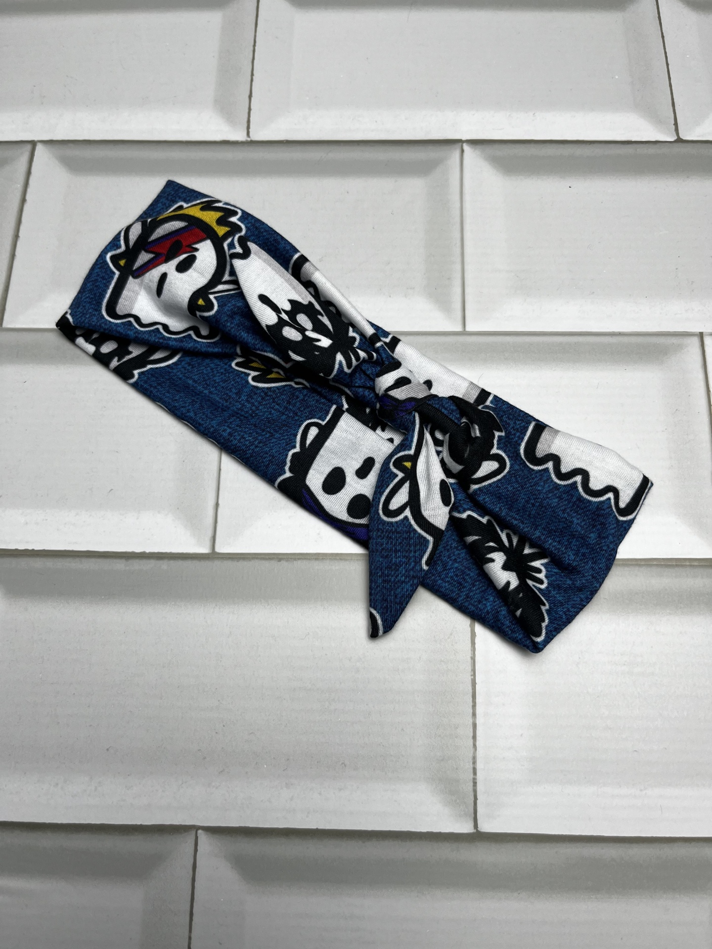 Bandana azul com estampas coloridas sobre azulejos brancos