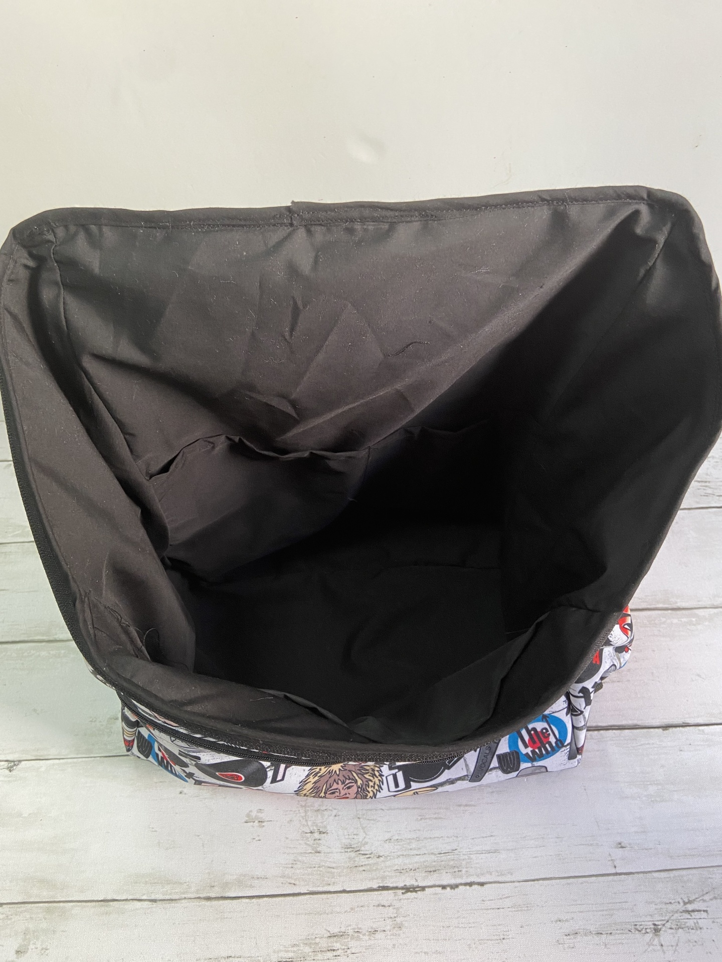 Saco forrado a preto com padrão colorido no exterior, sobre madeira clara.