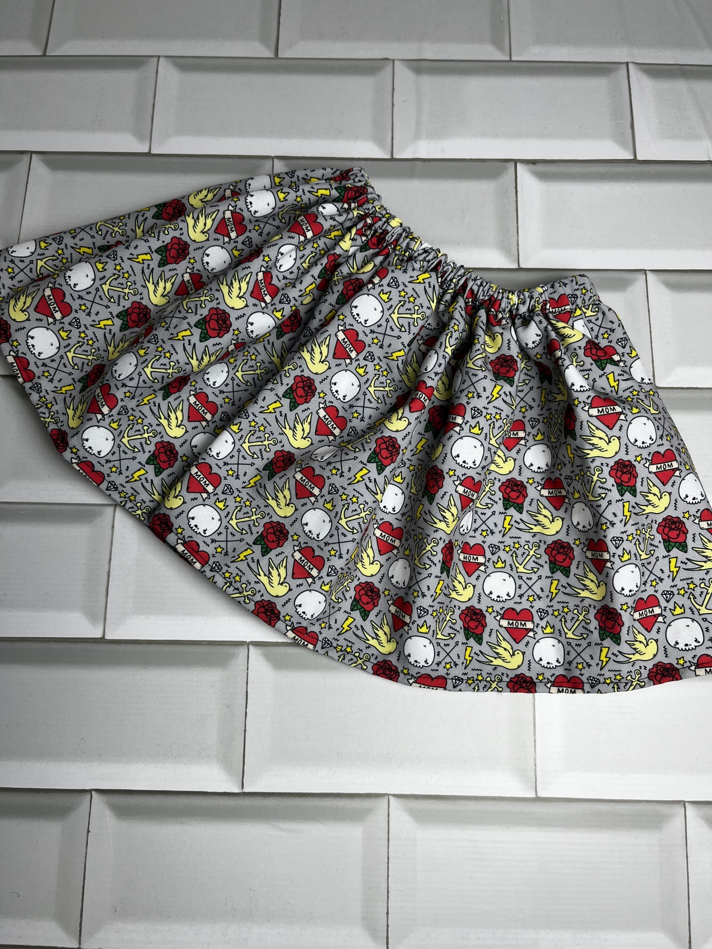 saia cinzenta com padrão colorido e cintura elástica sobre azulejos brancos