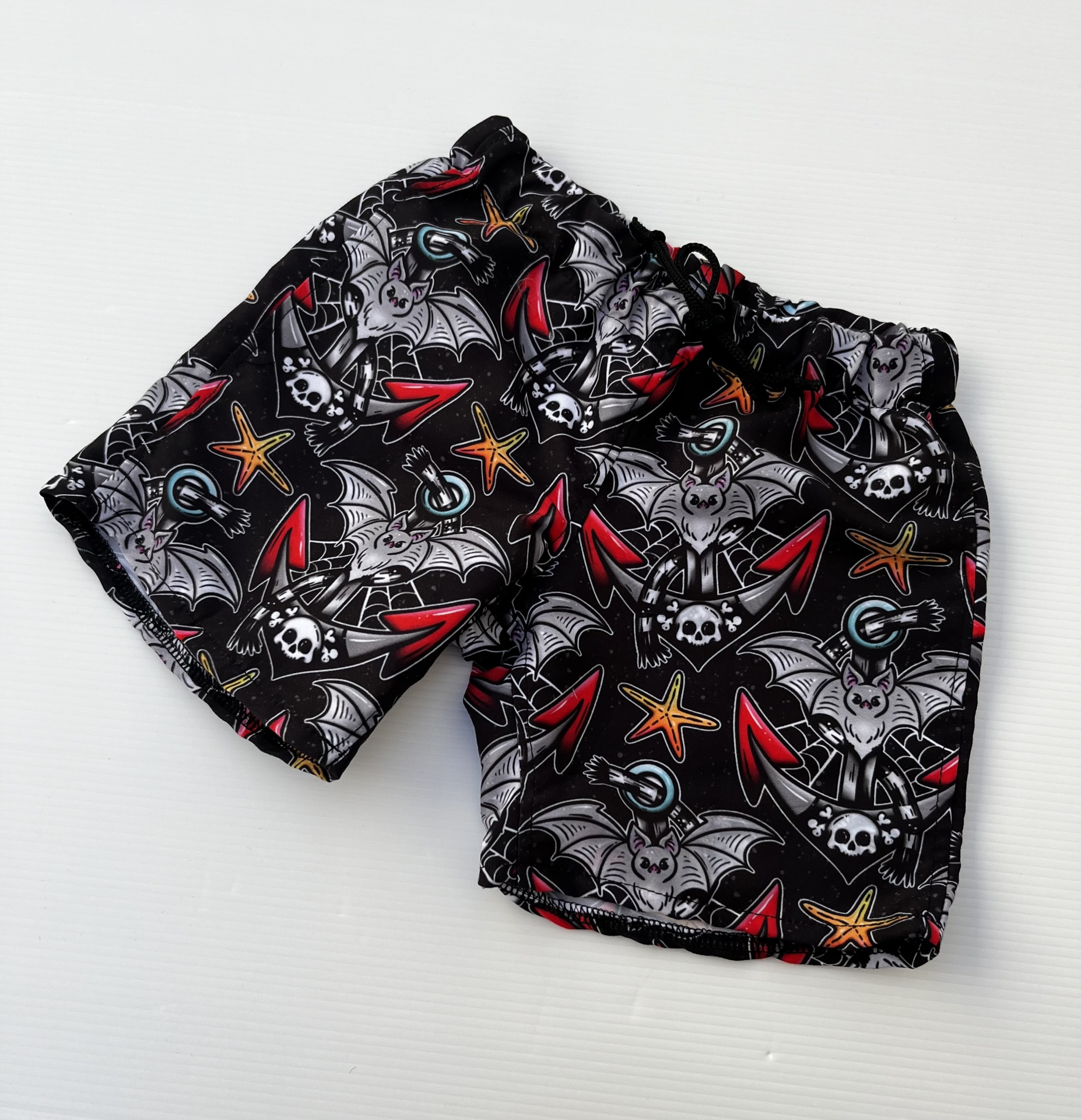 Calções pretos com padrão colorido de morcegos e caveiras