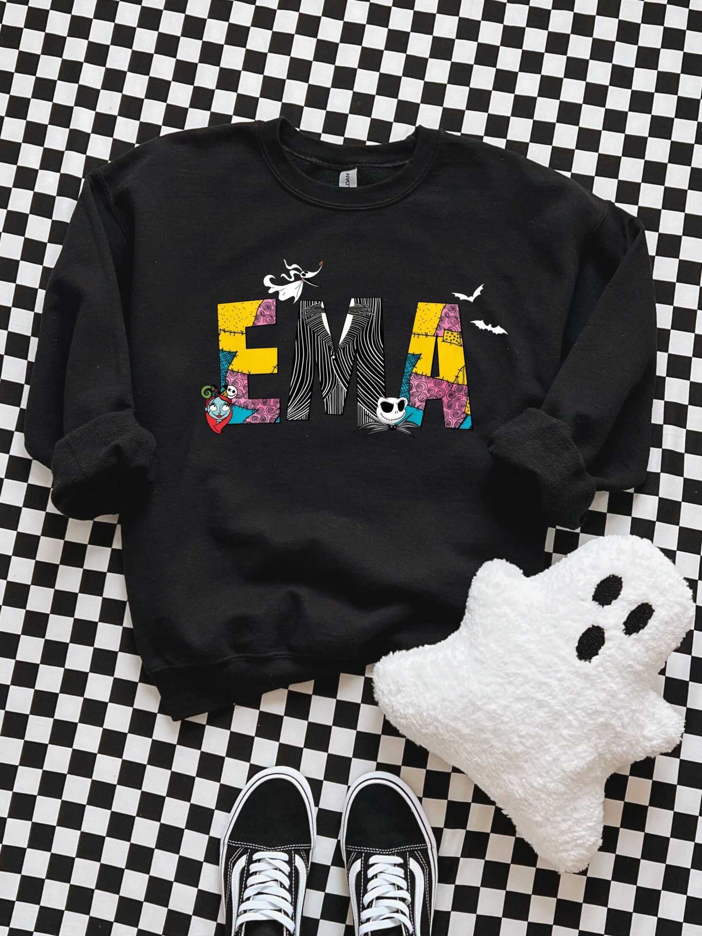 Sweatshirt preta com texto 'EMA' colorido e peluche fantasma em fundo quadriculado