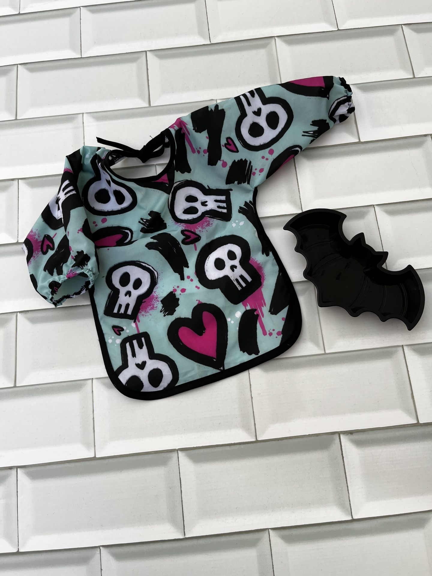 Babete de manga comprida com padrão de caveiras e coração e prato em forma de morcego