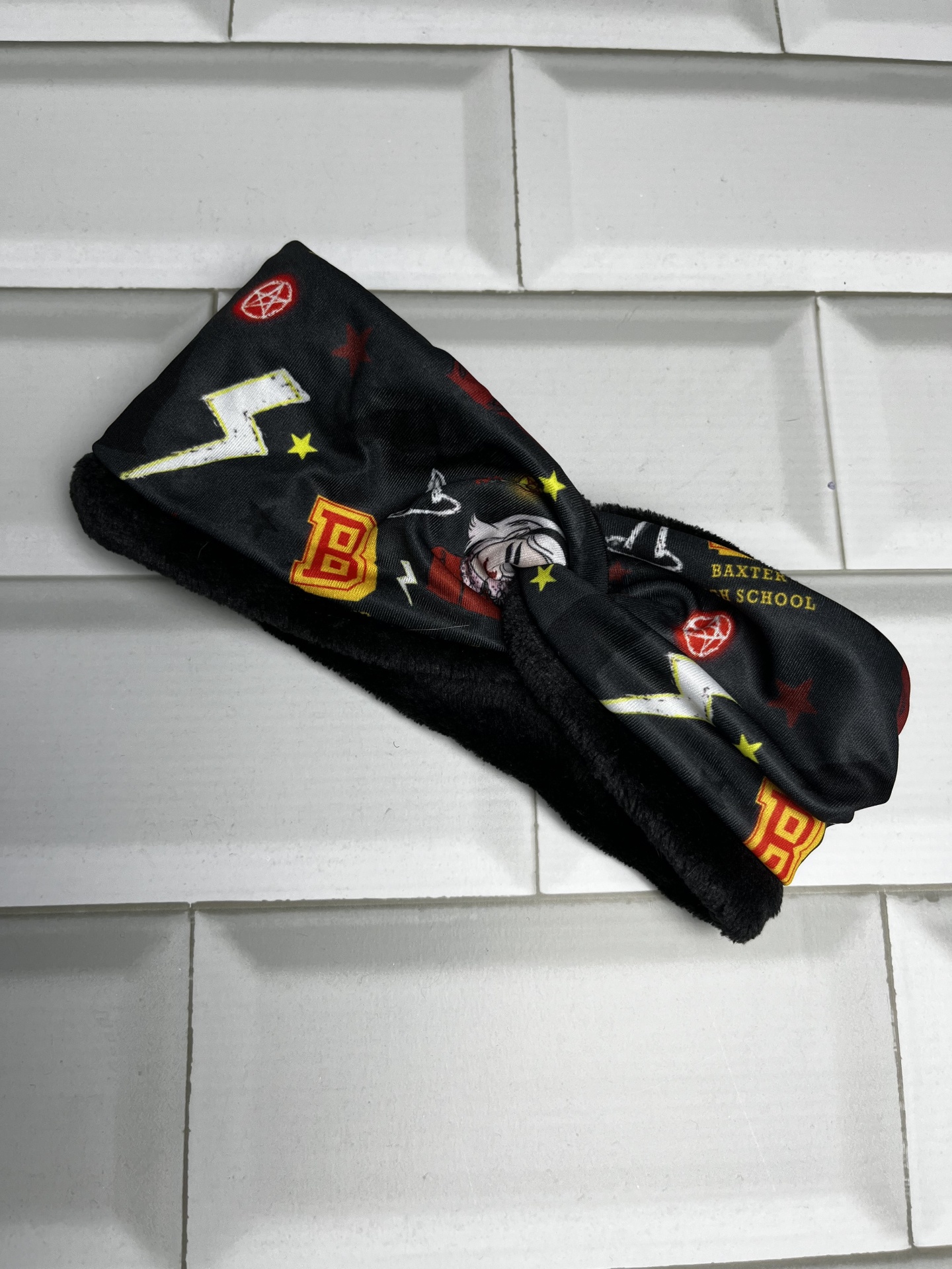Bandana preta com desenhos coloridos e texto parcial 'BAXTER SCHOOL'