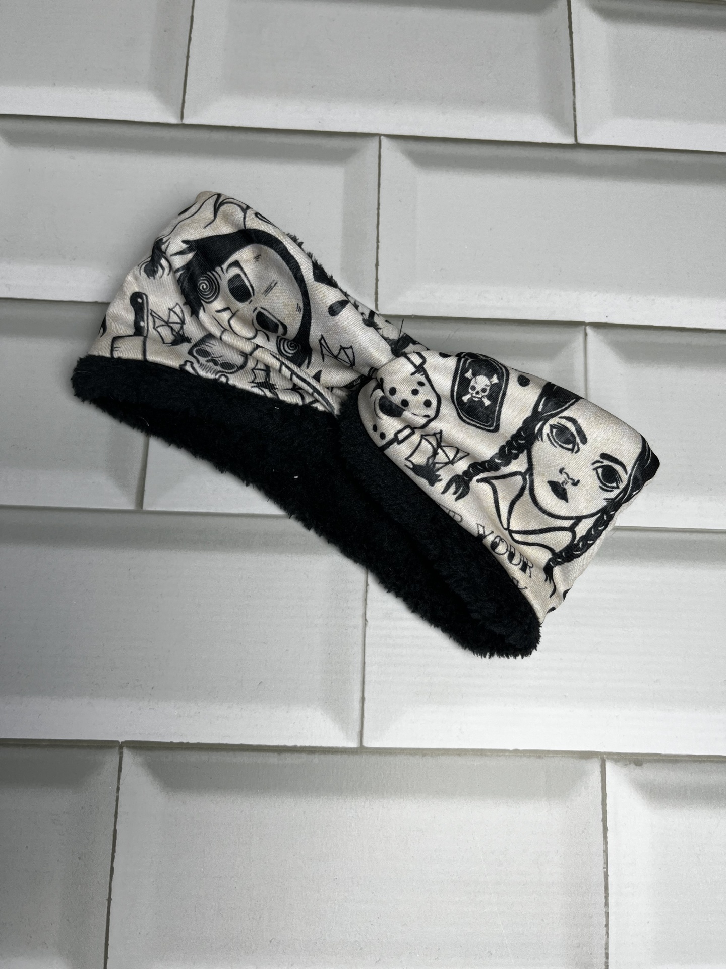 Faixa de tecido com padrão desenhado a preto e branco, com interior felpudo preto