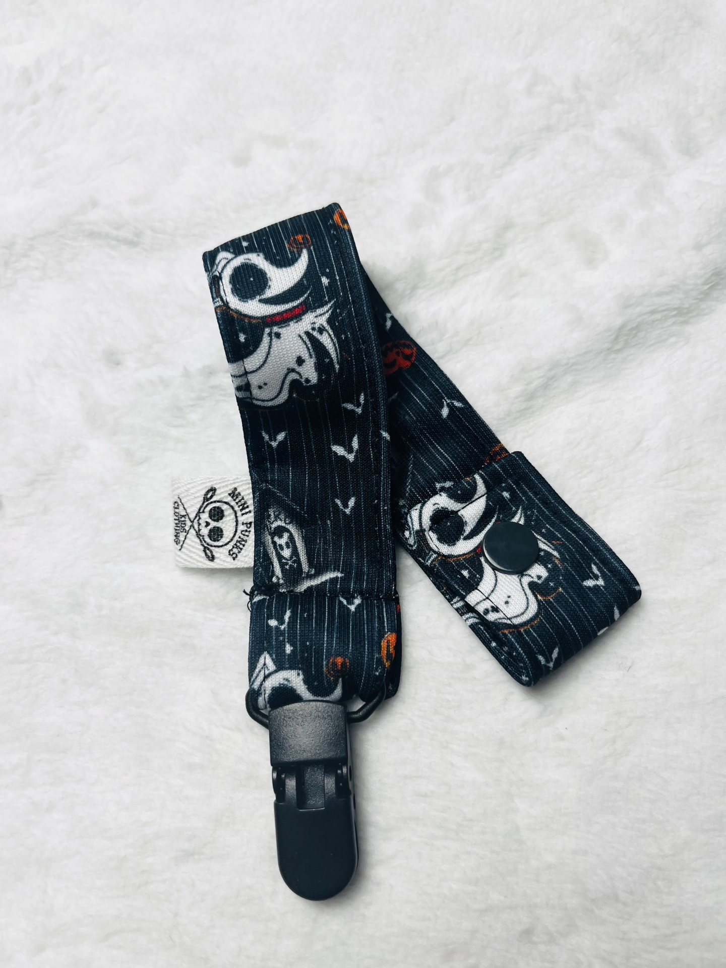 Correia preta com padrão de cães brancos e clipe preto sobre fundo branco