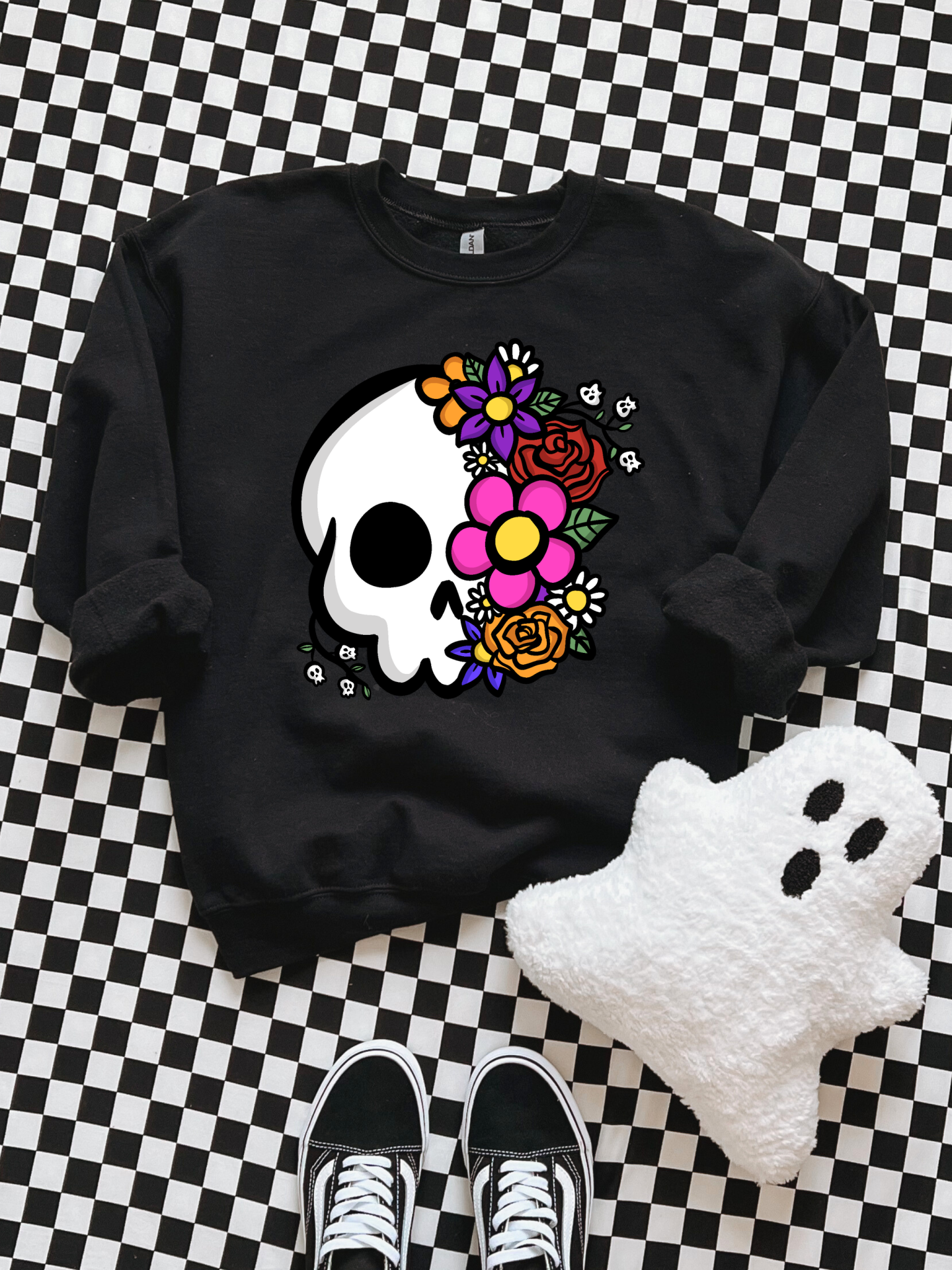 Sweatshirt preta com caveira e flores coloridas sobre fundo xadrez preto e branco