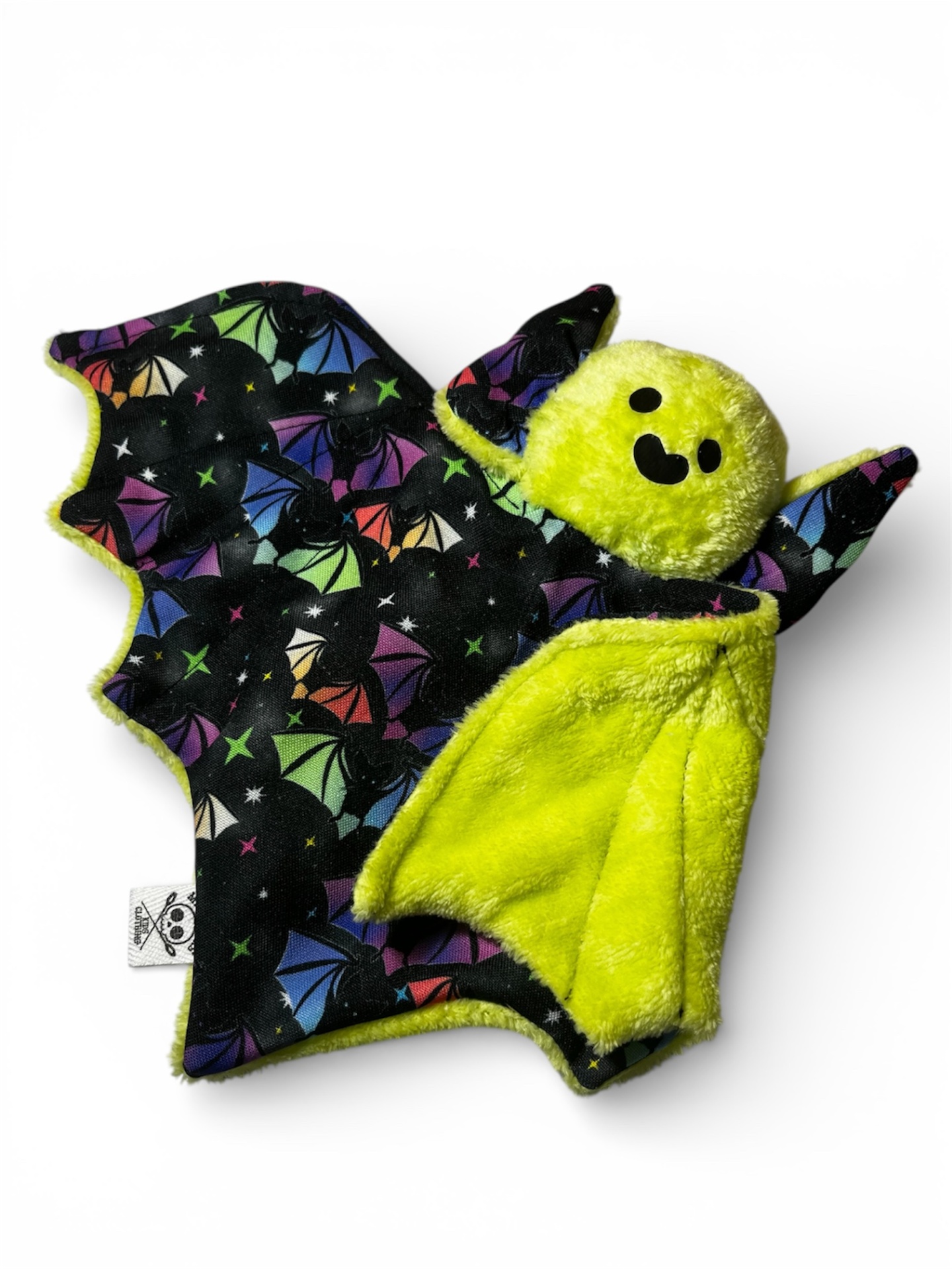 Brinquedo de morcego de pelúcia amarelo com asas pretas coloridas e padrão de morcegos.