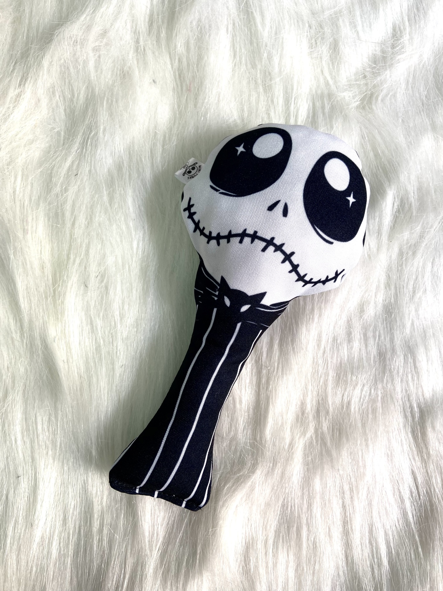 Brinquedo de pelúcia com rosto assustador preto e branco sobre tecido branco