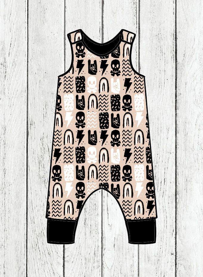 Macacão infantil com padrão de caveiras, raios e arcos em bege, preto e branco sobre fundo de madeira branca