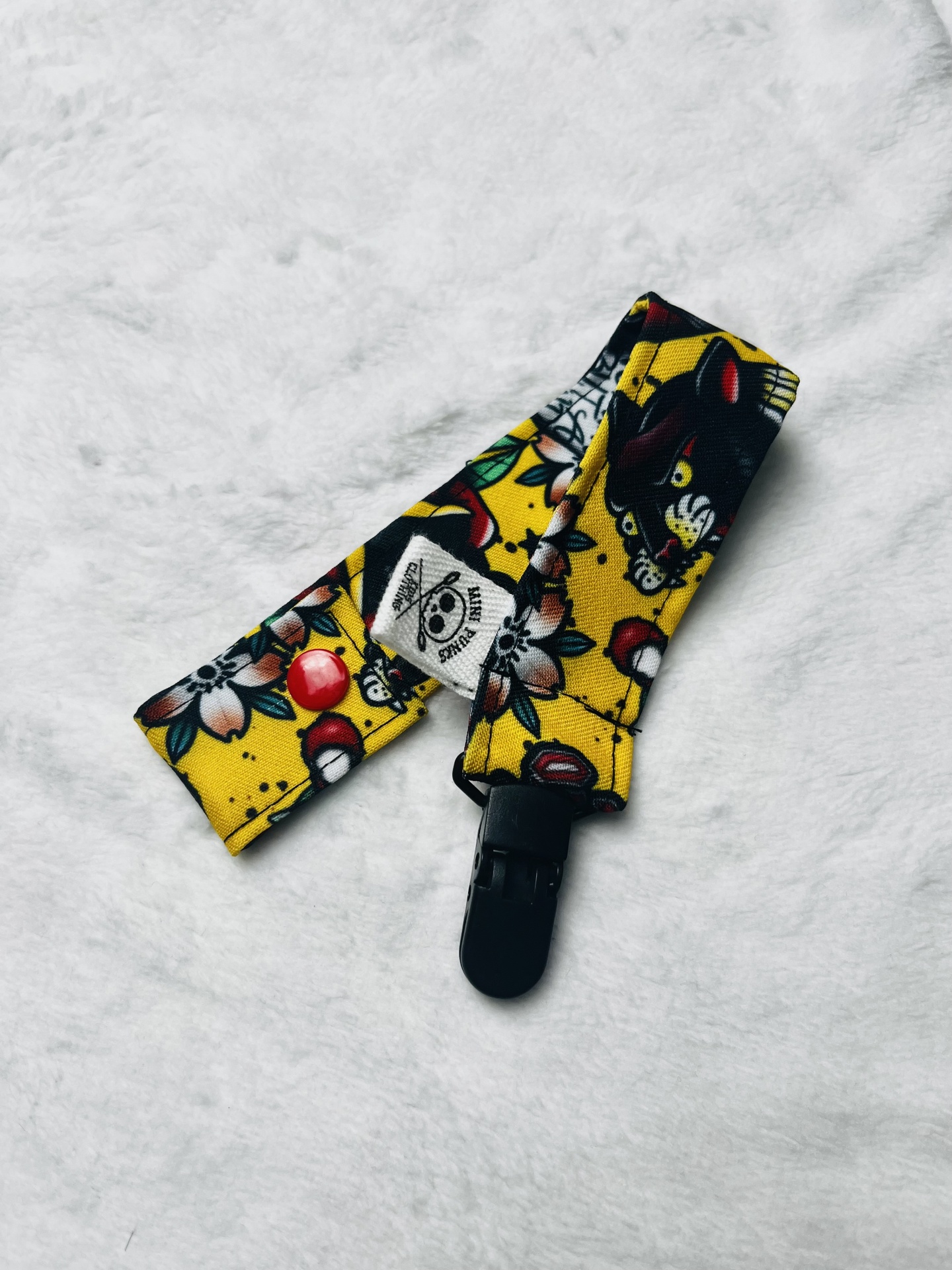 Clip de tecido amarelo com padrão colorido e clipe preto sobre fundo branco macio