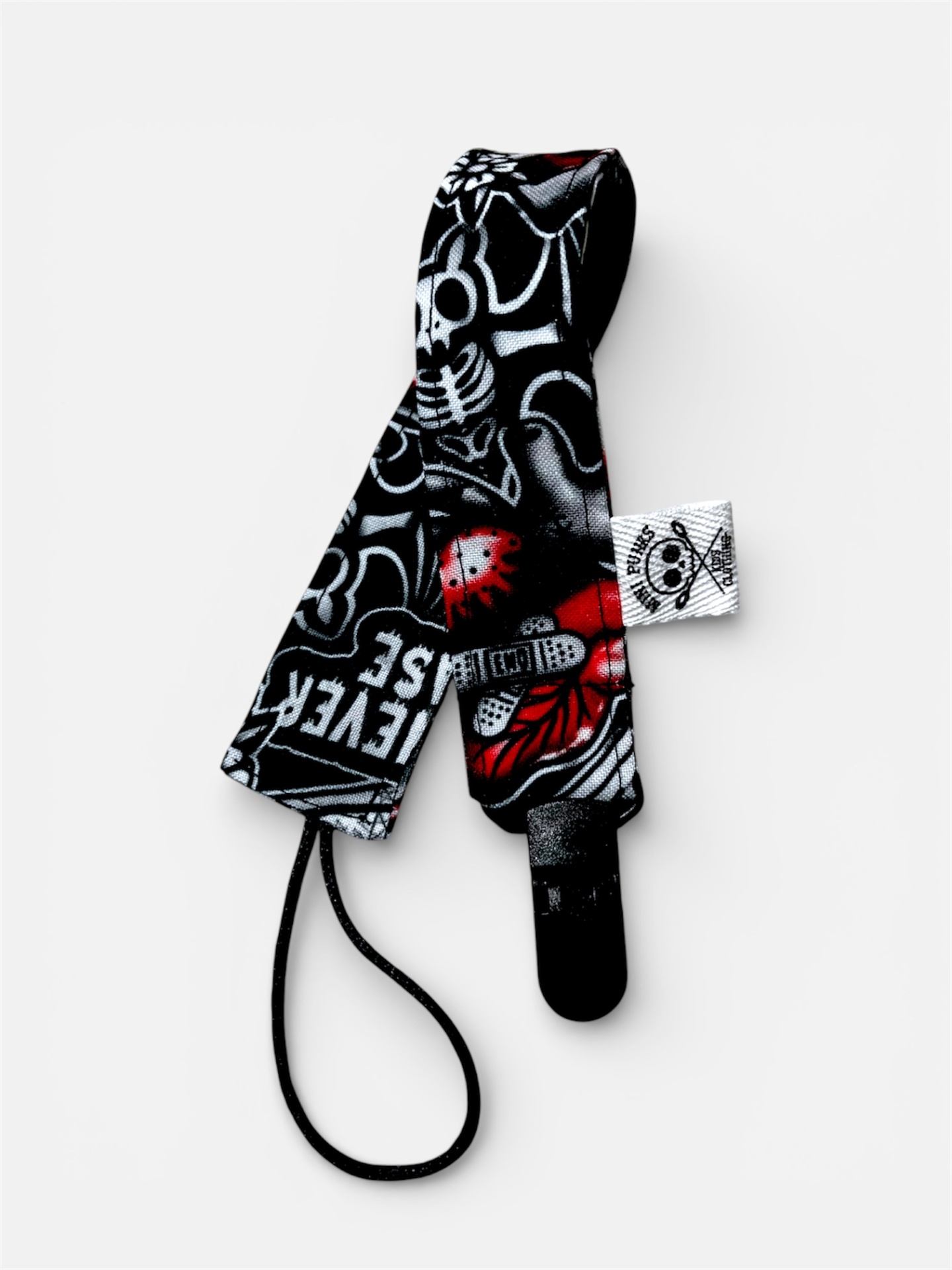 Correia tecido preta com estampados em branco e vermelho com padrão de caveiras e texto, etiqueta branca e cordão.