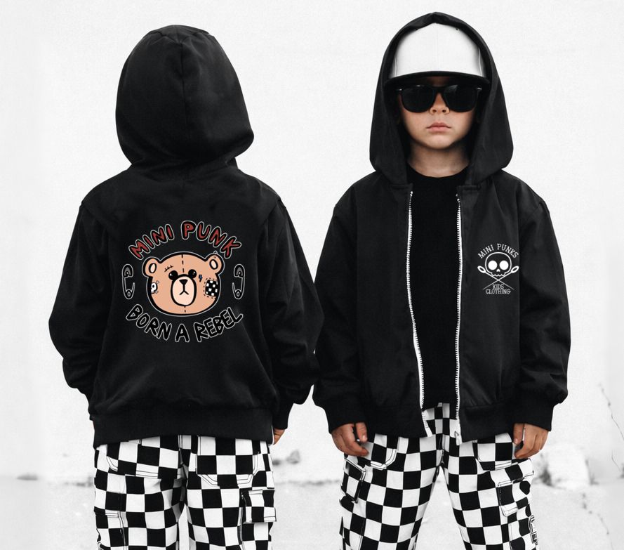 Casaco preto com estampas de urso e texto, calças quadriculadas pretas e brancas em criança com boné e óculos.