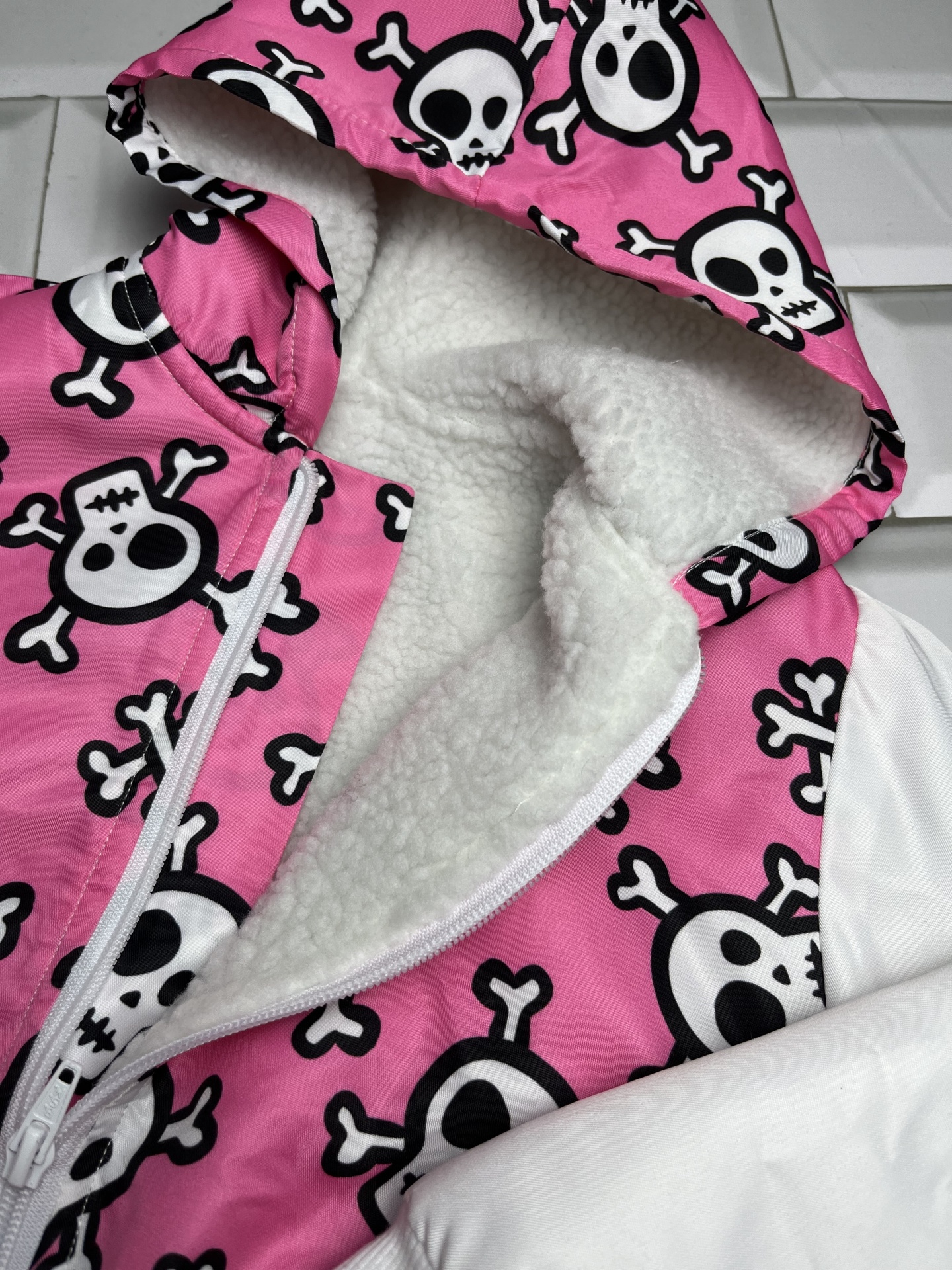 Casaco com padrão de caveiras em rosa e branco felpudo no interior do capuz