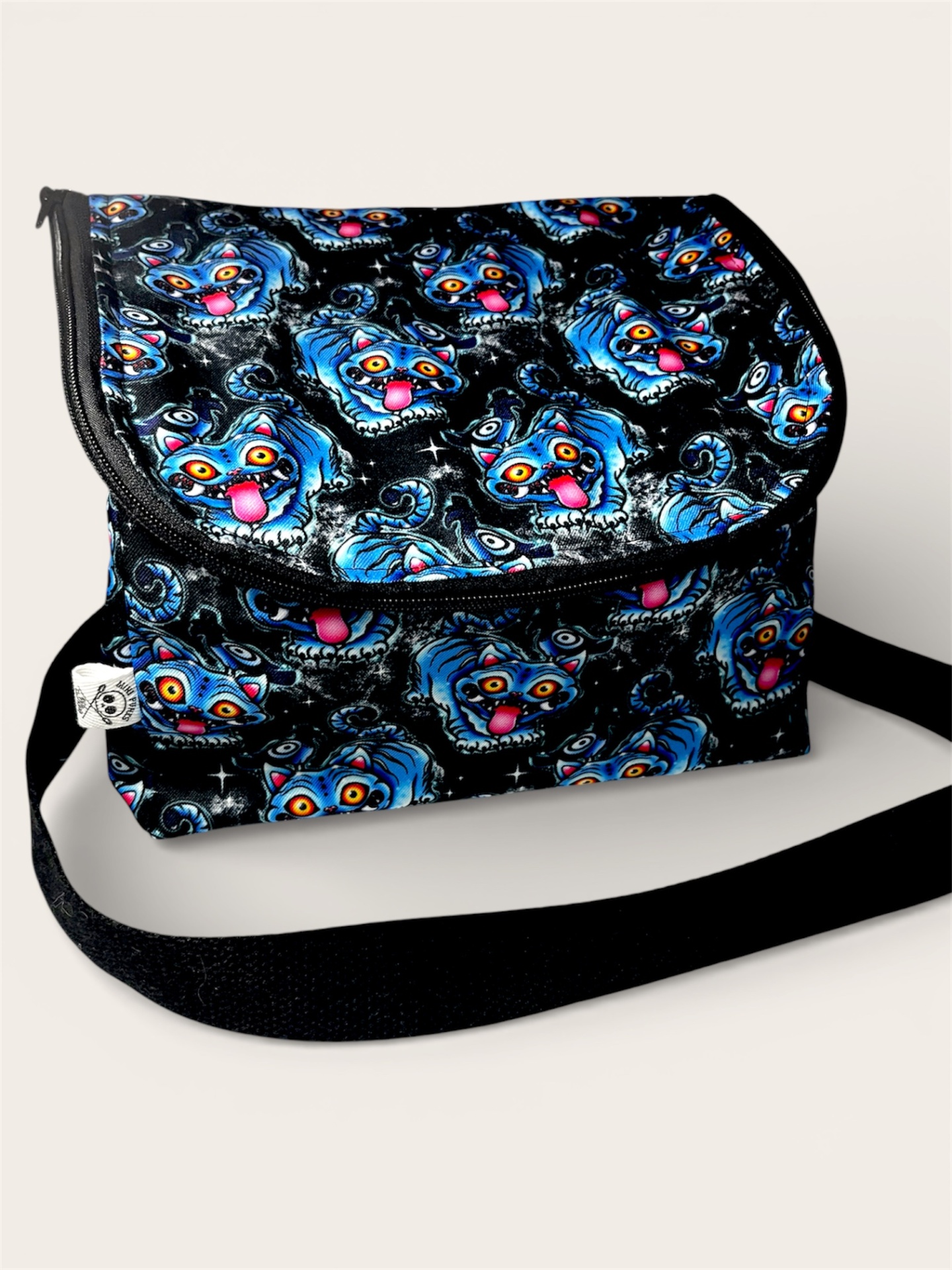 Mala tiracolo preta com padrão de faces de cães azuis