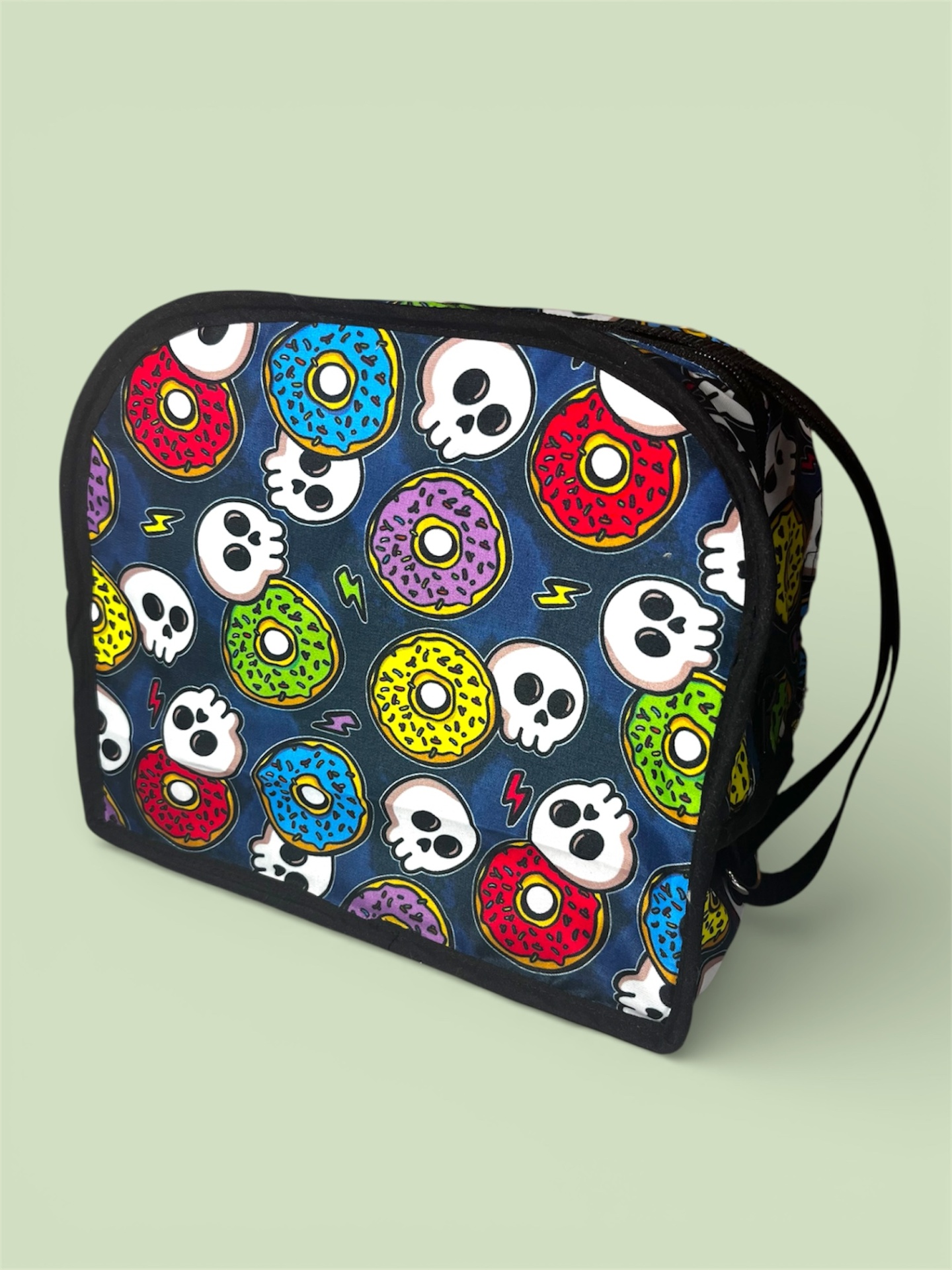 Bolsa quadrada com padrão colorido de donuts e caveiras sobre fundo azul escuro