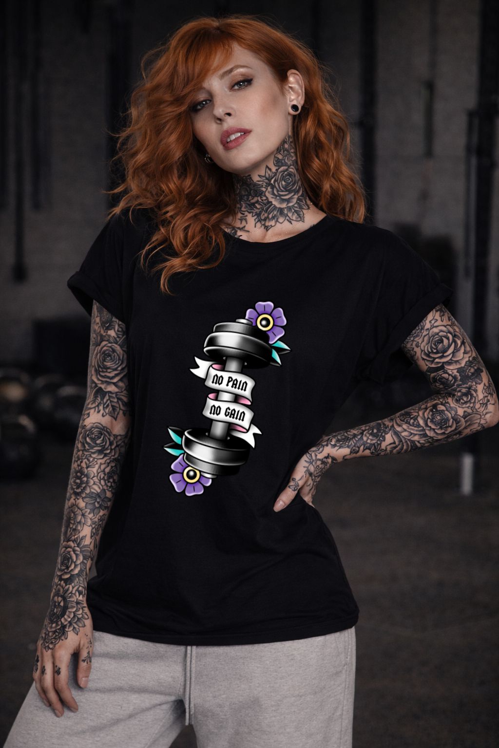 Mulher com tatuagens usando t-shirt preta com estampa NO PAIN NO GAIN e halter