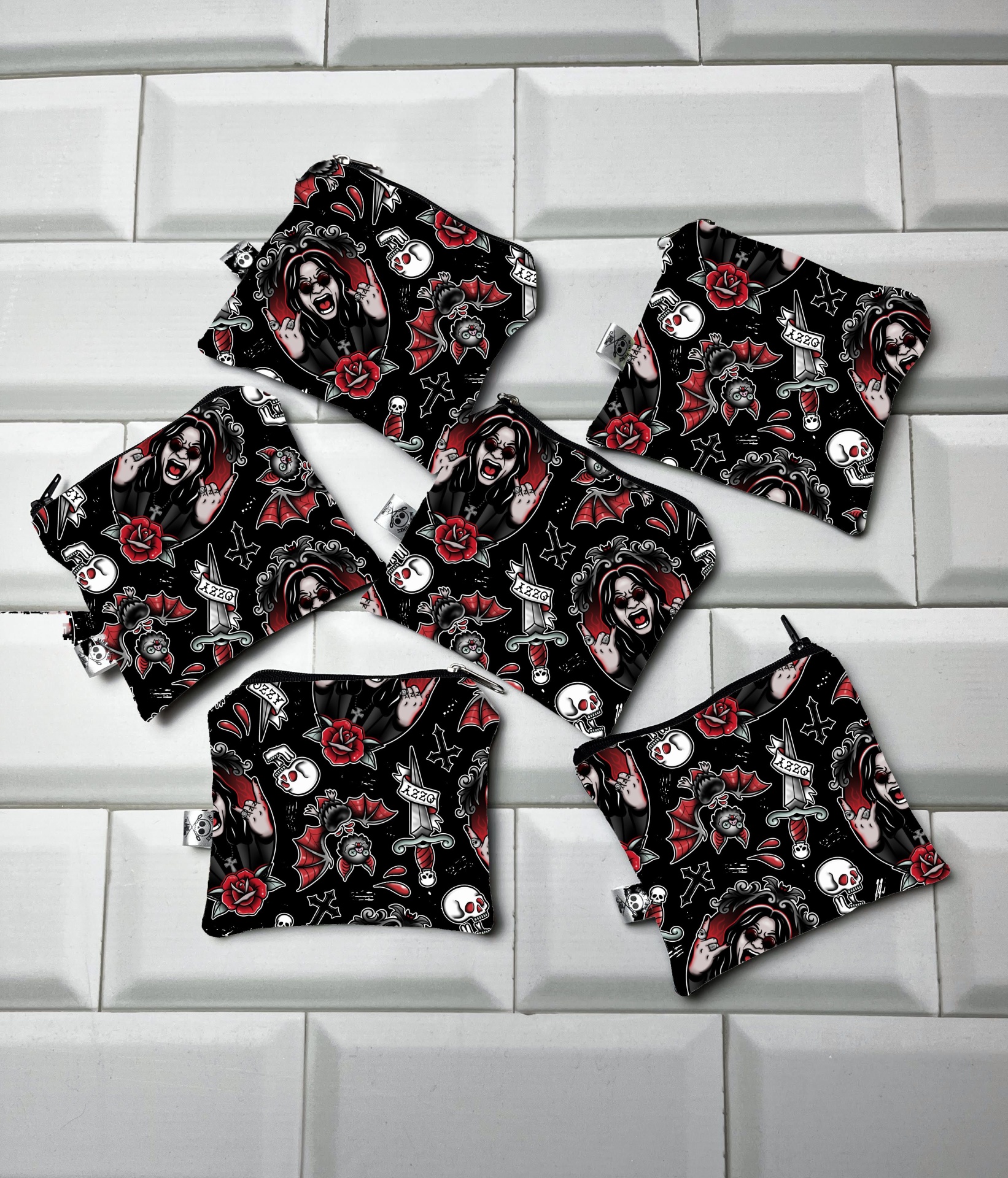 Seis saquinhos pequenos de tecido preto com padrão colorido de caveiras e rosas sobre azulejos brancos