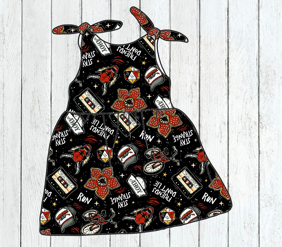 Vestido de criança com padrão colorido e texto em inglês sobre fundo preto