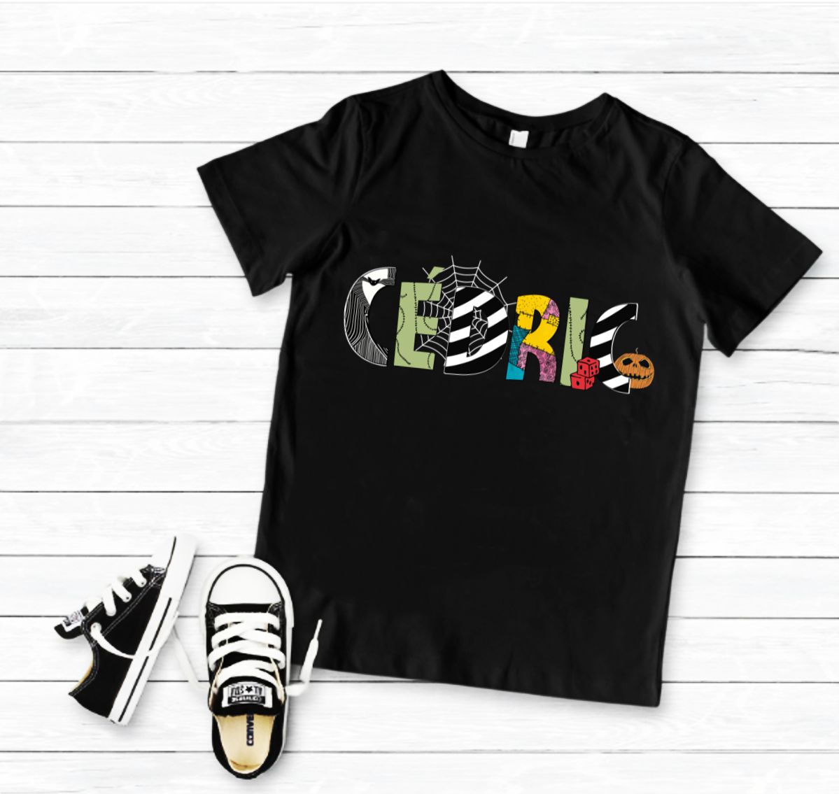 T-shirt preta com estampado colorido da palavra CEBRICS ao centro e sapatilhas pretas e brancas ao lado