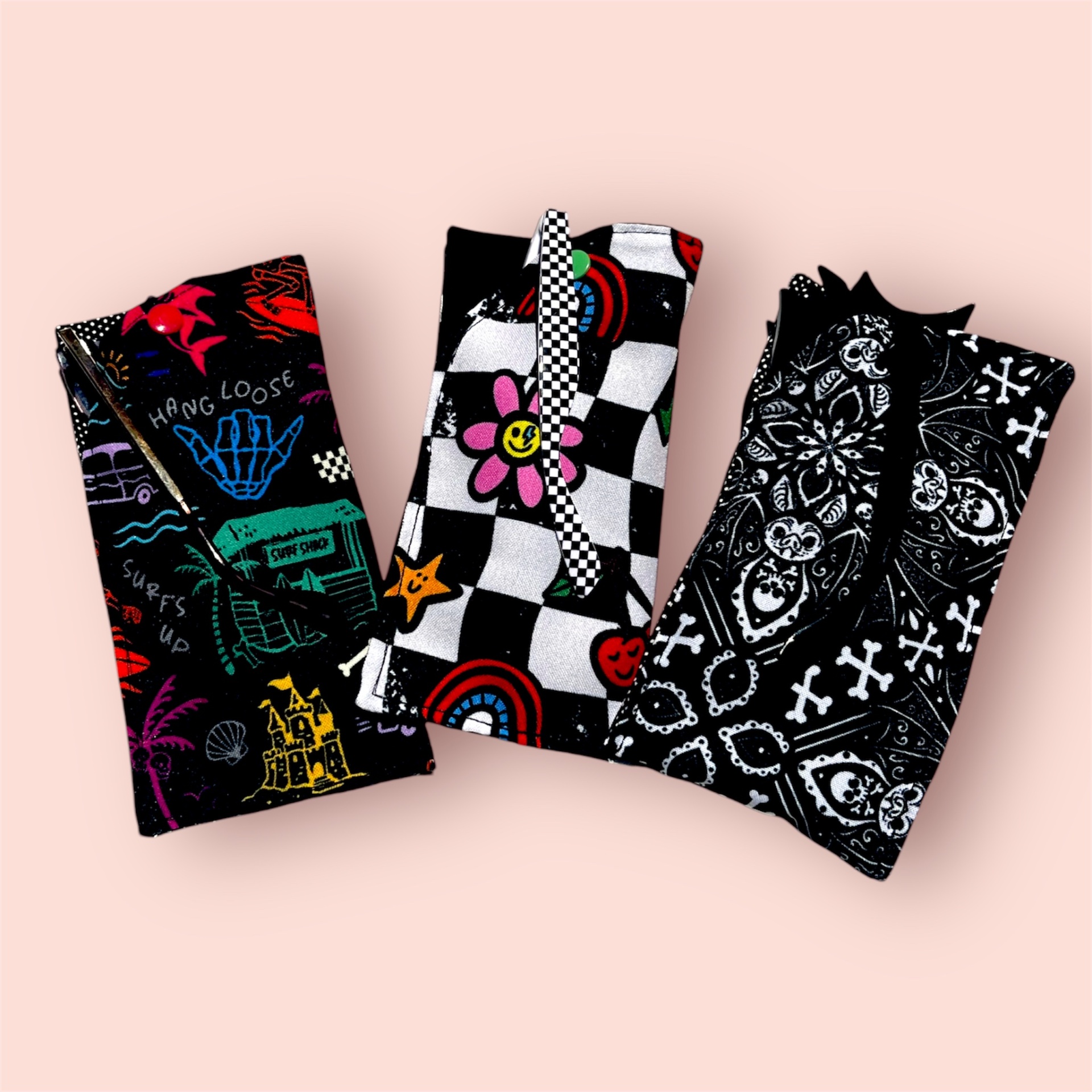 Três peças de roupa dobradas com diferentes padrões coloridos e fundo rosa