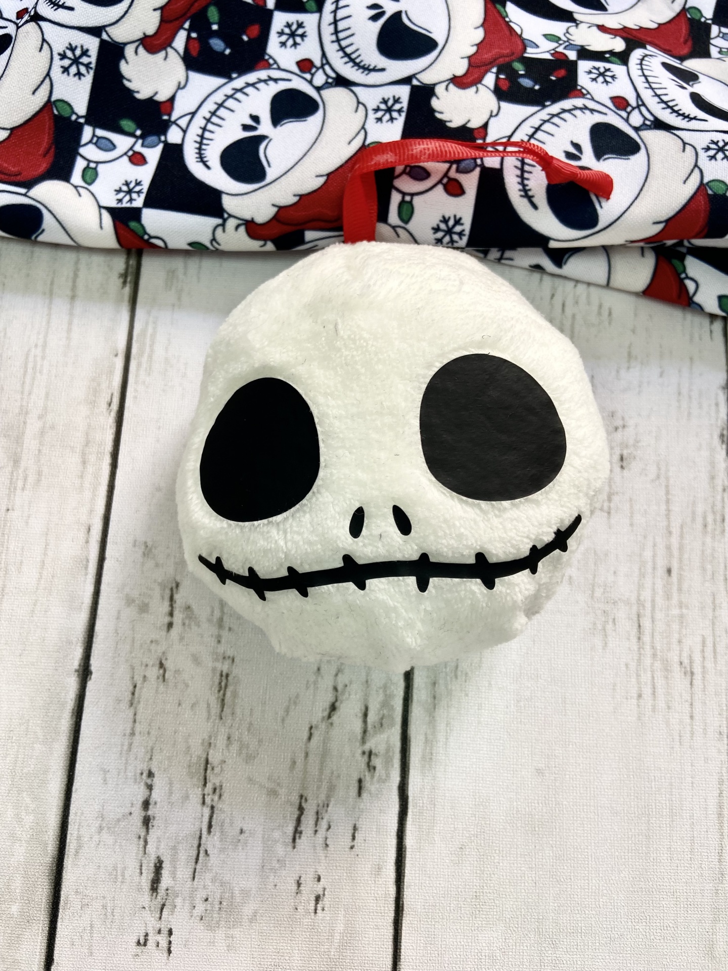 Pelúcia branca de crânio com laço vermelho pendurado sobre madeira branca