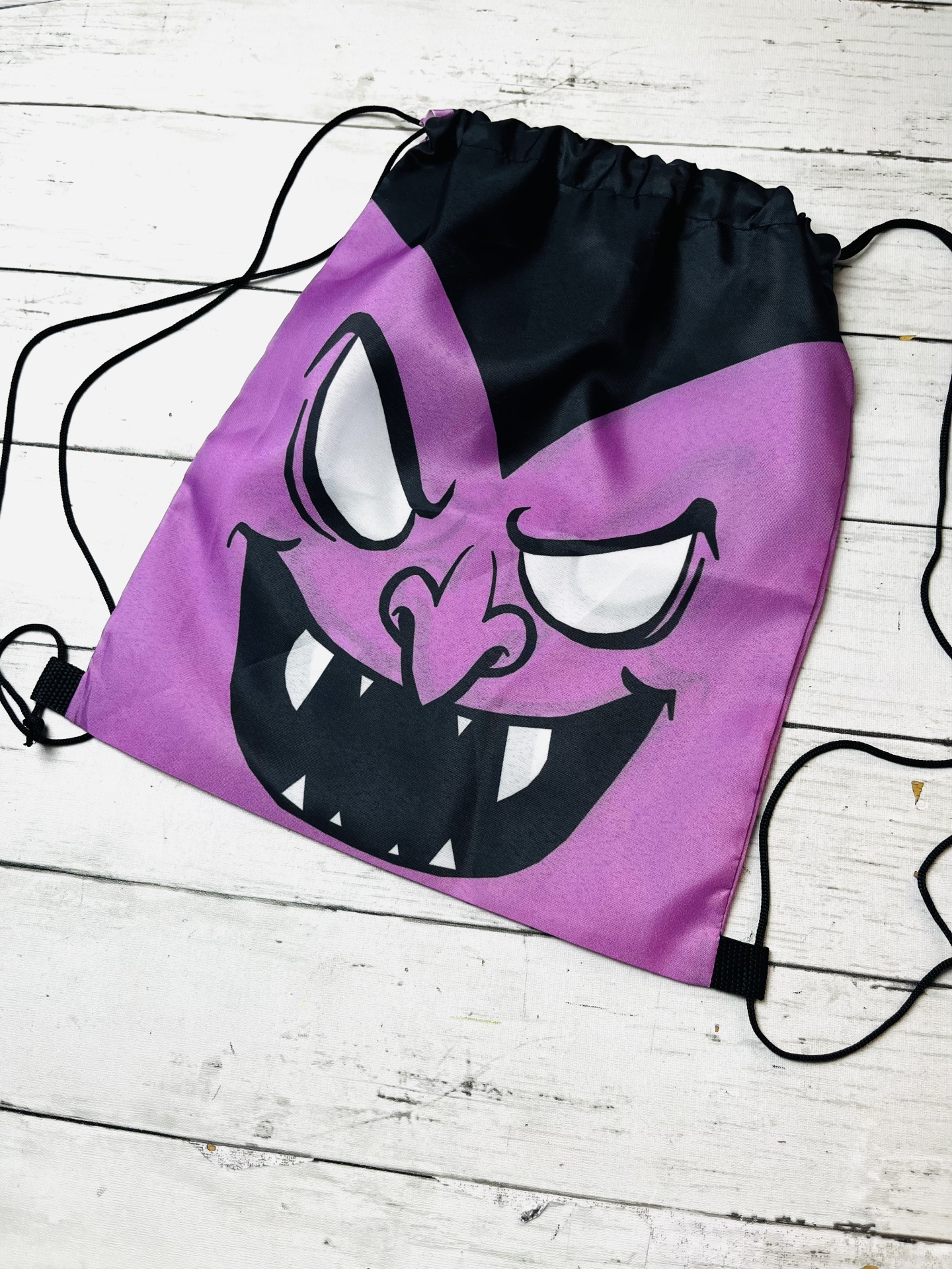 Saco mochila roxo com rosto malicioso desenhado