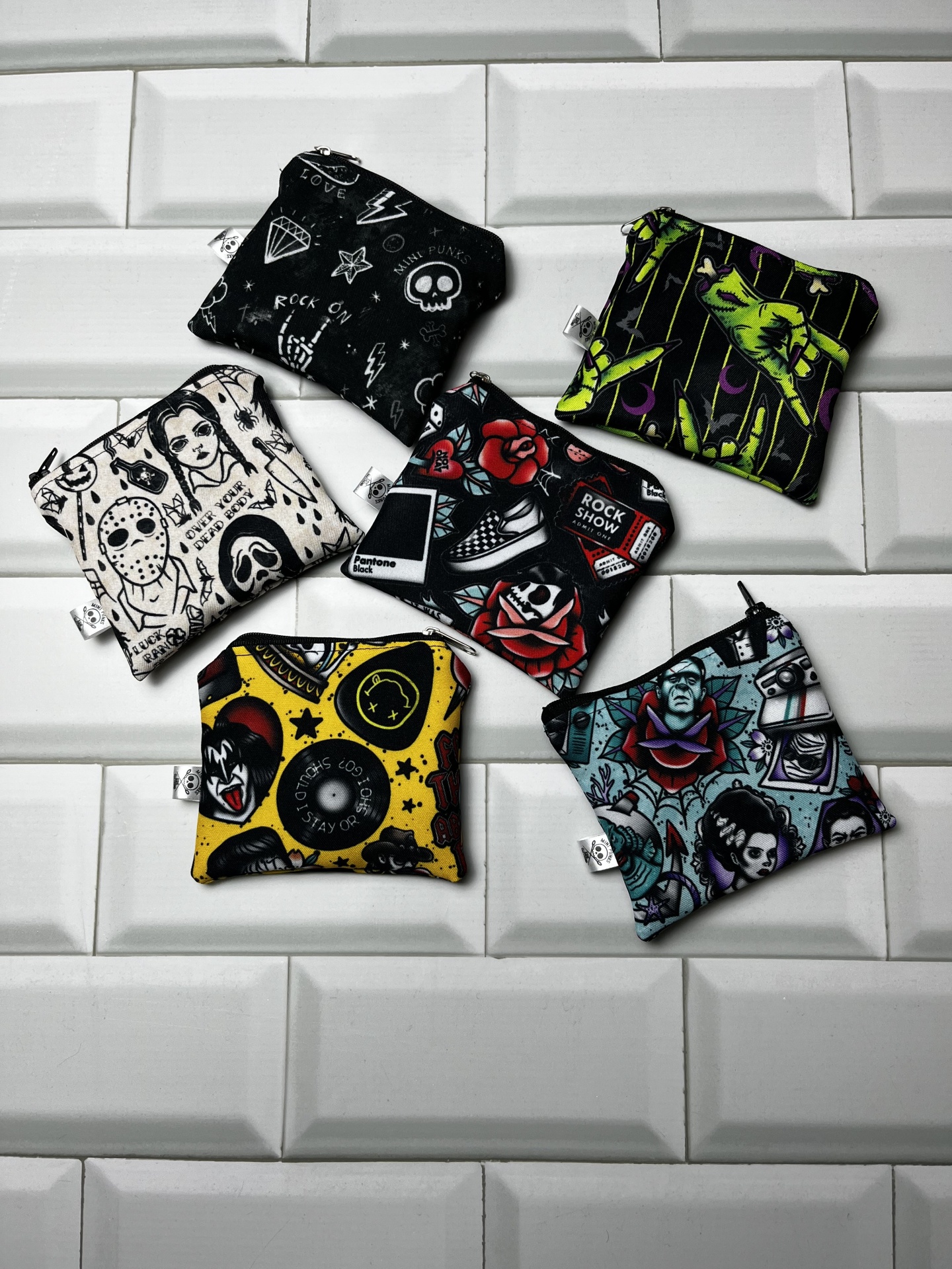 Pequenas bolsas de tecido com designs gráficos coloridos e preto e branco sobre azulejos brancos 3D.