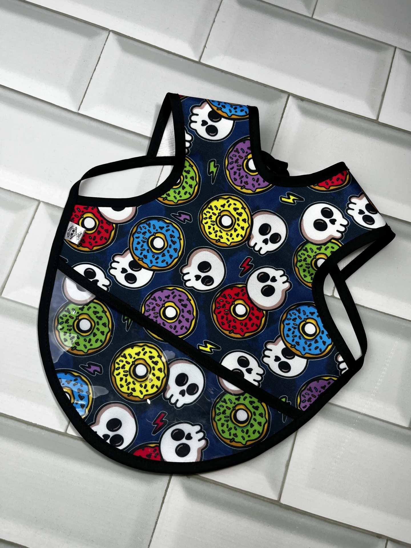 Babete para bebé com padrão de donuts e caveiras coloridos