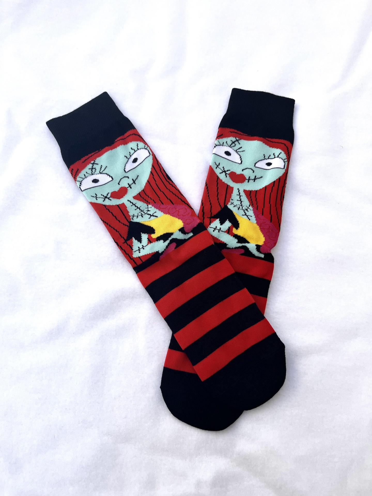 Meias com riscas pretas e vermelhas e rosto de personagem colorido