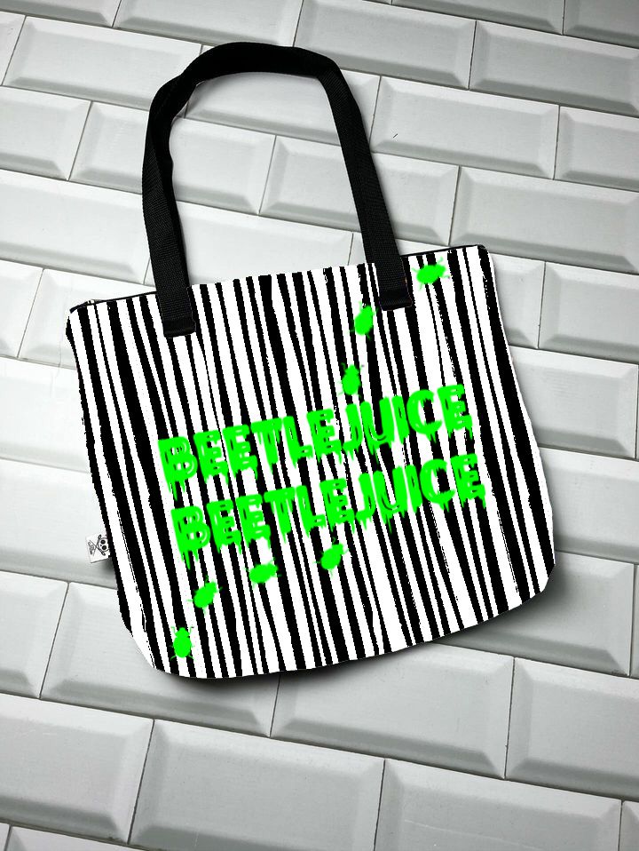 Mala tote bag riscas pretas e brancas com texto verde BEETLEJUICE sobre azulejos brancos