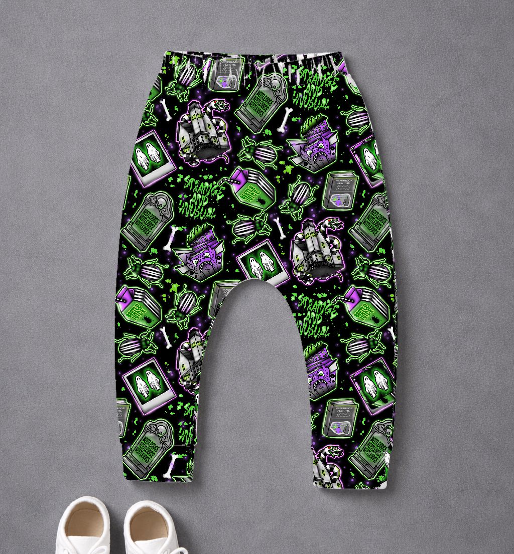 calças para criança com padrão assustador em preto, verde e roxo sobre fundo cinzento