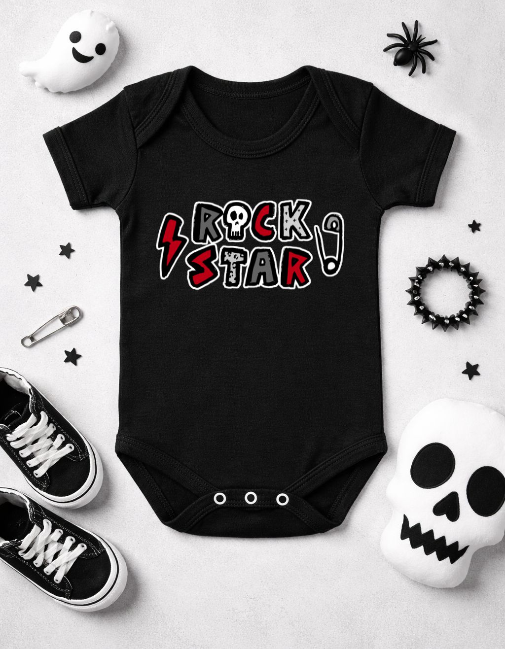 Body preto de bebé com texto ROCK STAR rodeado de acessórios e brinquedos temáticos