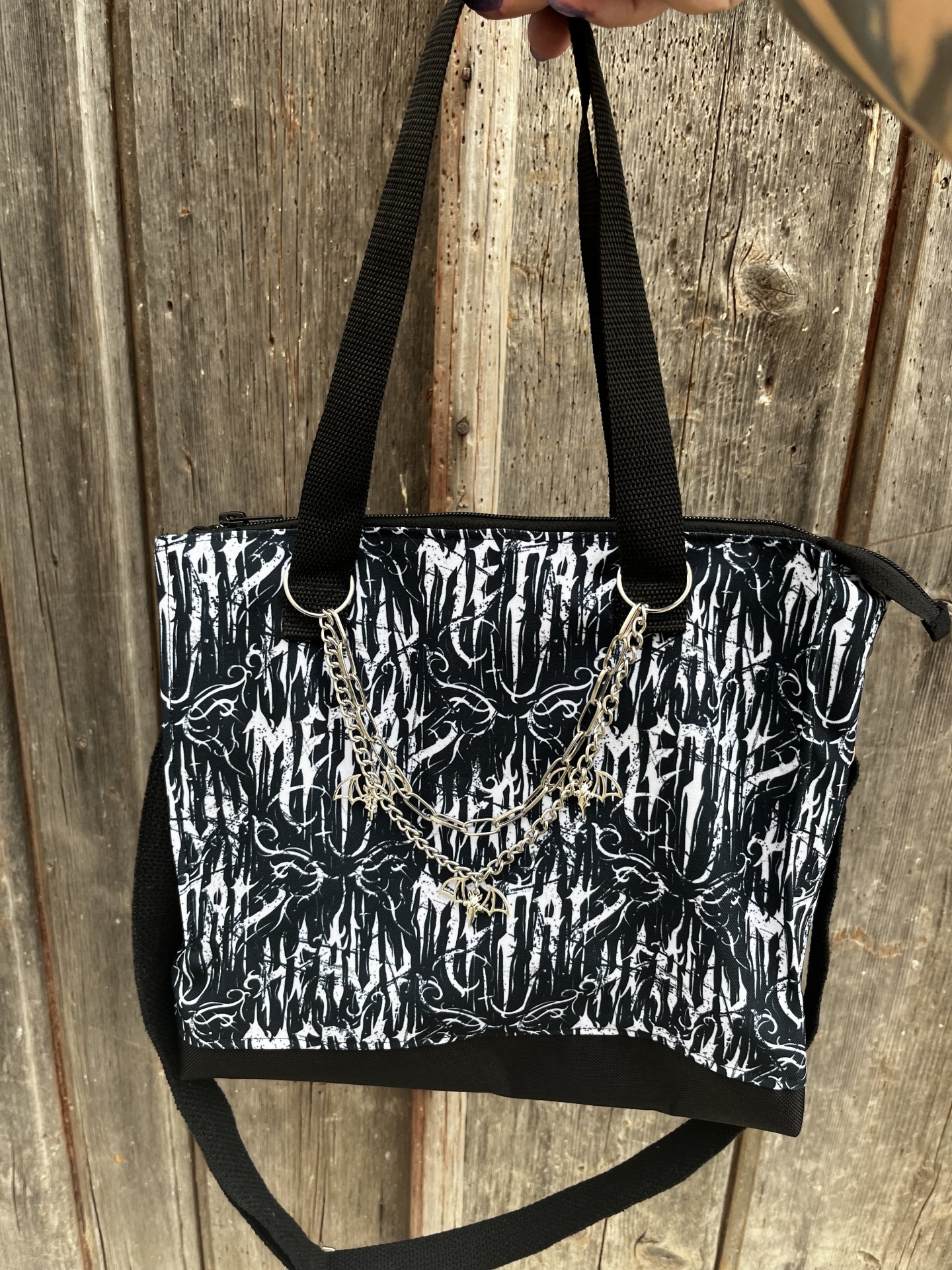 Mala preta e branca com padrão gráfico e corrente prateada