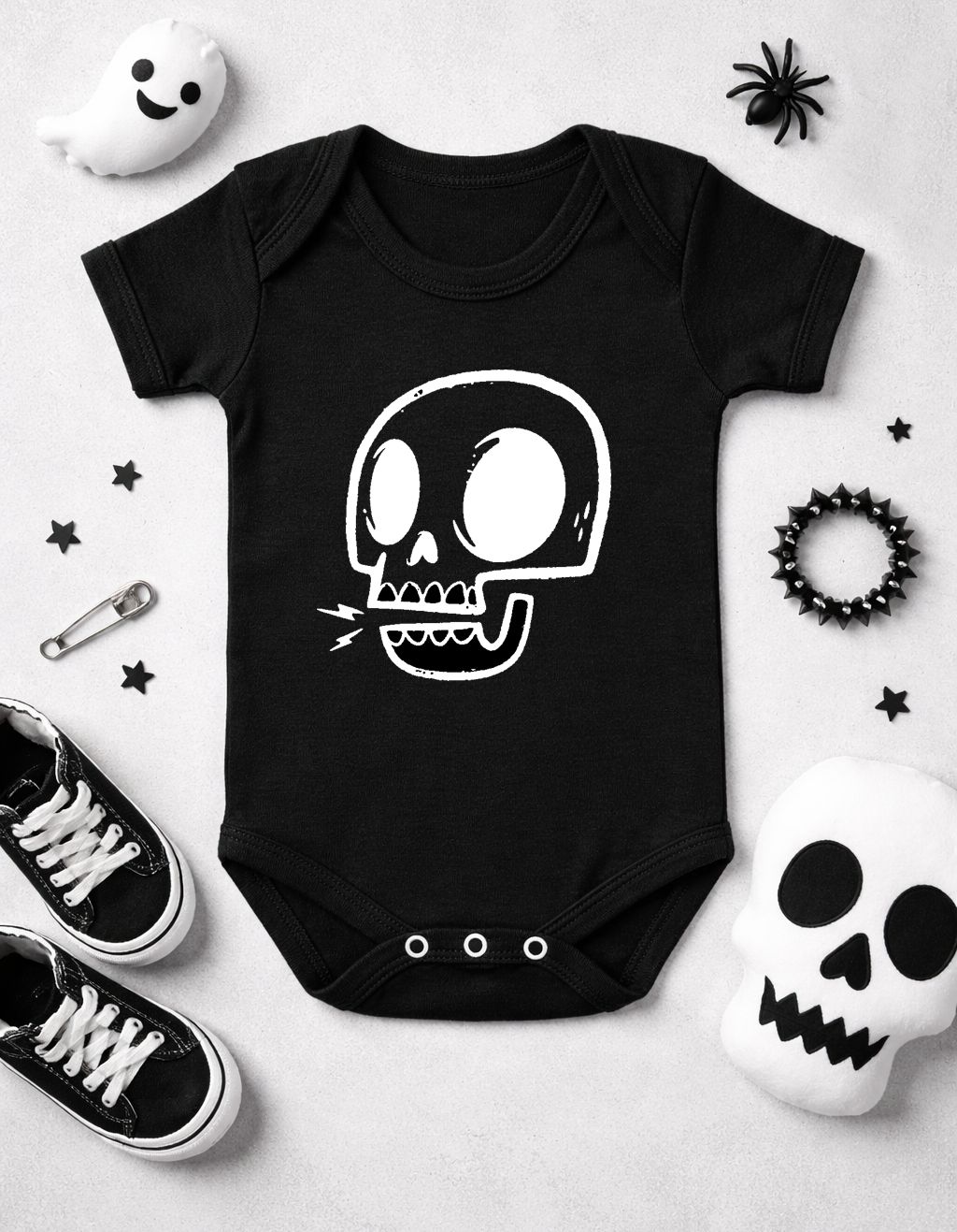 Body de bebé preto com estampado de caveira branco rodeado por ténis, pulseira preta e brinquedos de Halloween