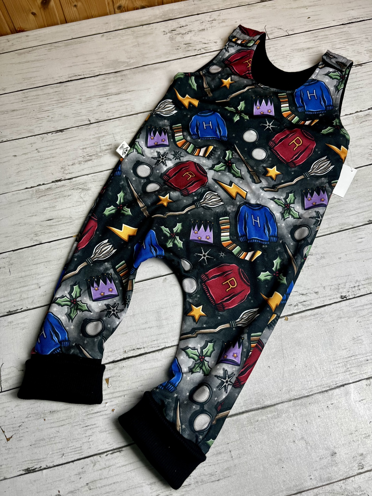 macacão infantil colorido com padrão de camisolas, varinhas, estrelas e óculos