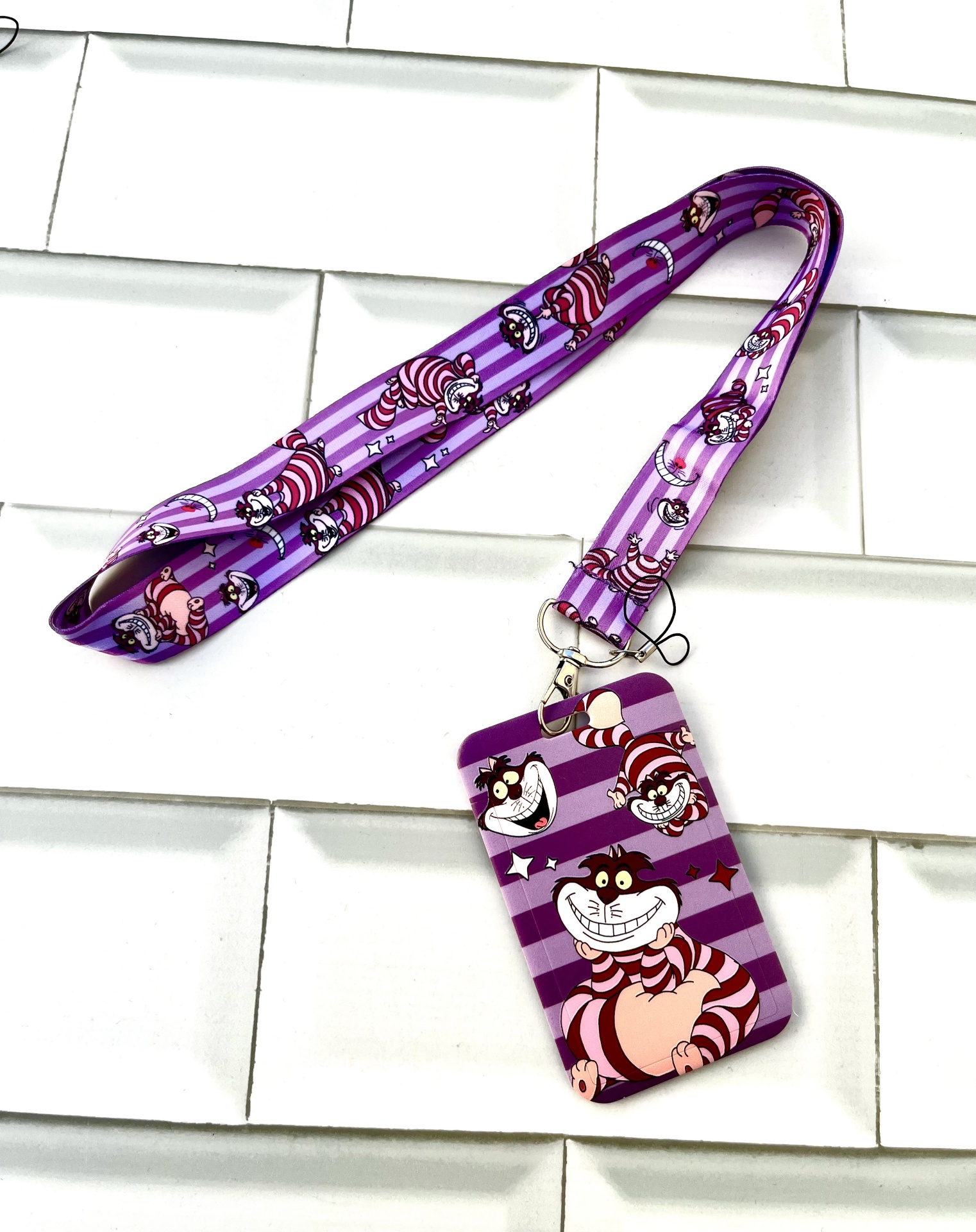 Cracha roxo com personagens do Gato Cheshire e cordão combinando