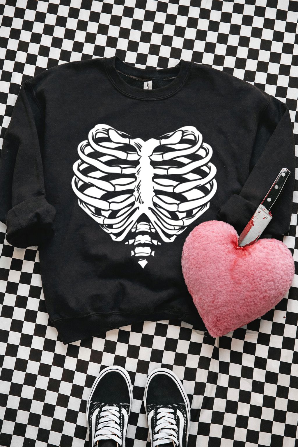 Sweatshirt preta com estampa de caixa torácica em forma de coração e peluche rosa em formato de coração com faca