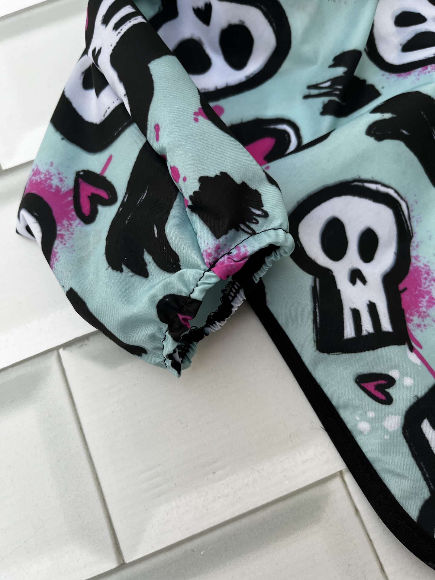 Manga elástica com padrão de caveiras e corações numa superfície branca texturizada
