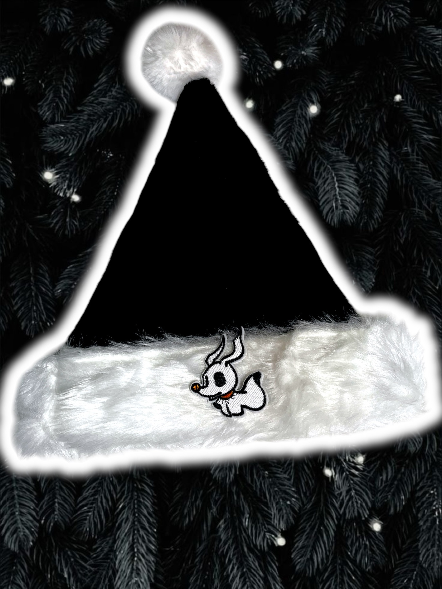 Chapéu de Natal preto e branco com personagem bordado, sobre ramos de pinheiro com luzes