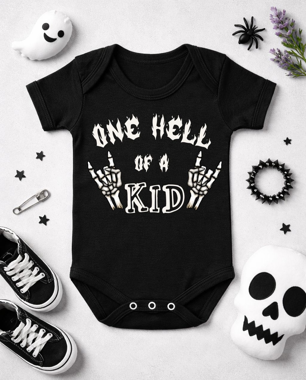 Body bebê preto com texto branco e esqueletos, rodeado de objetos como brinquedos Halloween e ténis