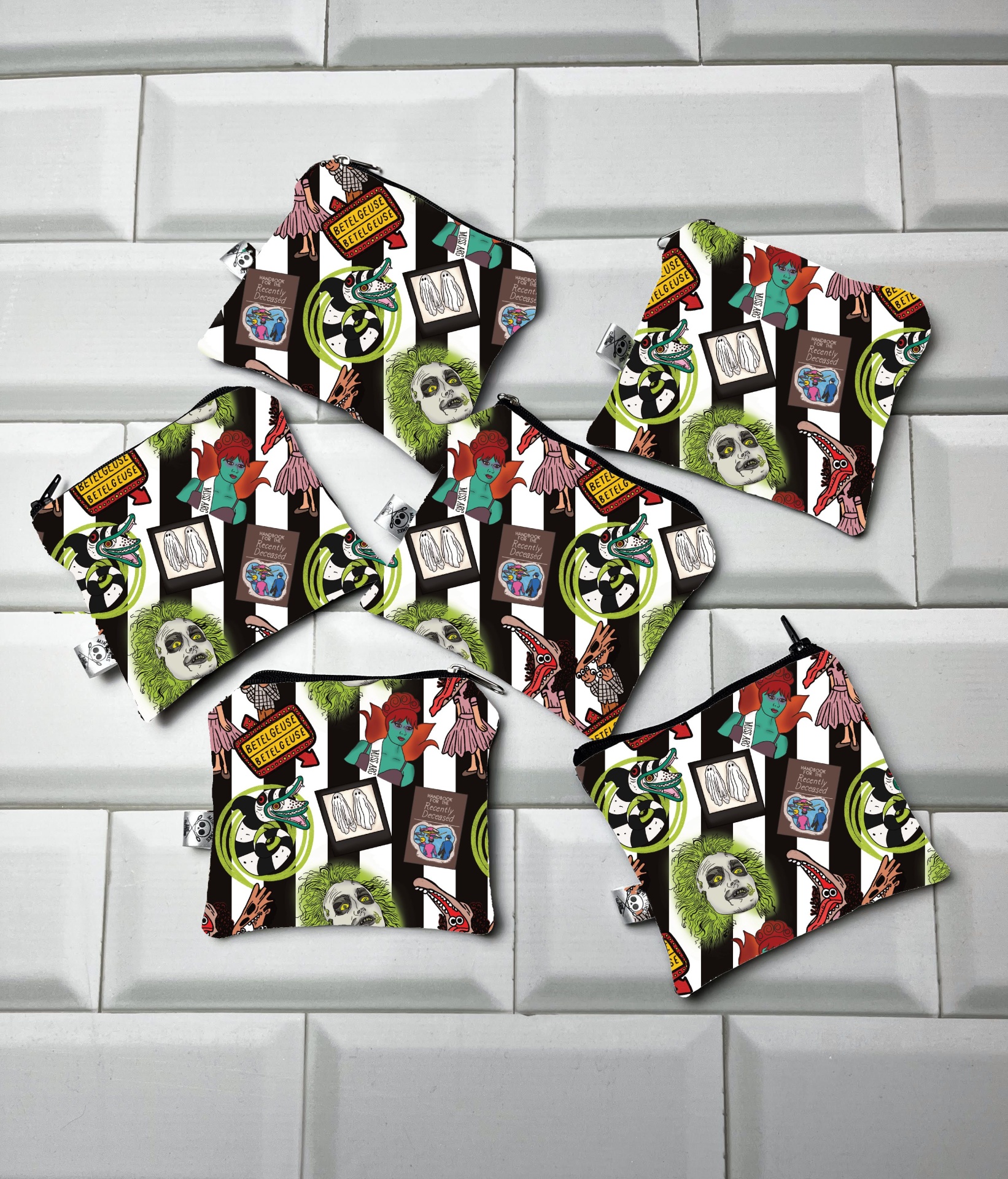 Sete bolsas coloridas de tecido com estampas de bonecos e textos em inglês sobre azulejos brancos