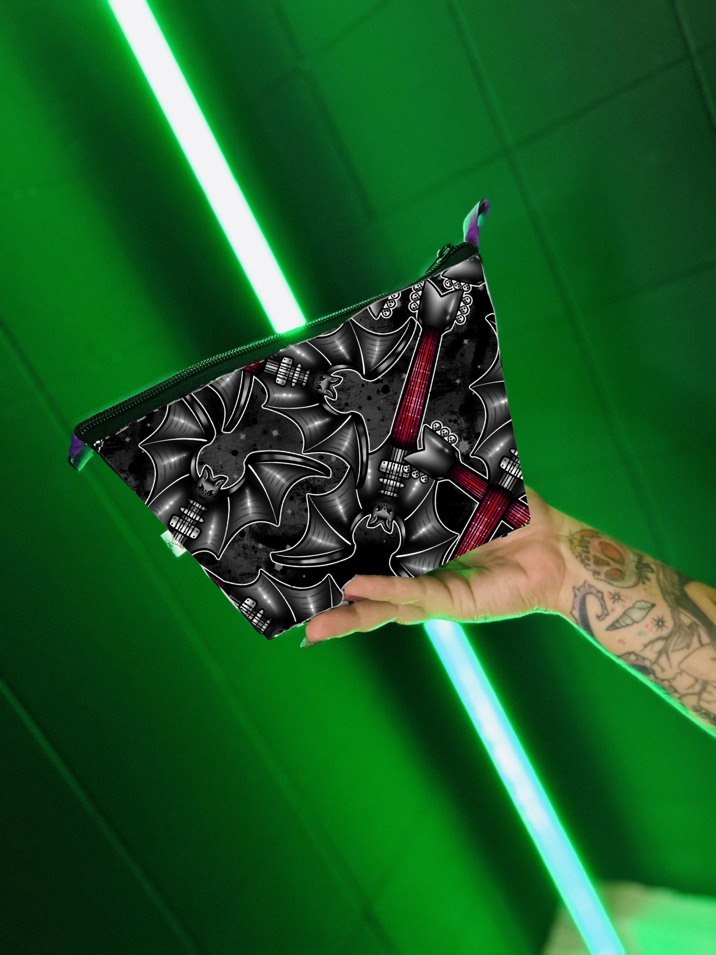 Bolsa pequena triangular com padrão de morcegos pretos e cruz vermelha num fundo verde