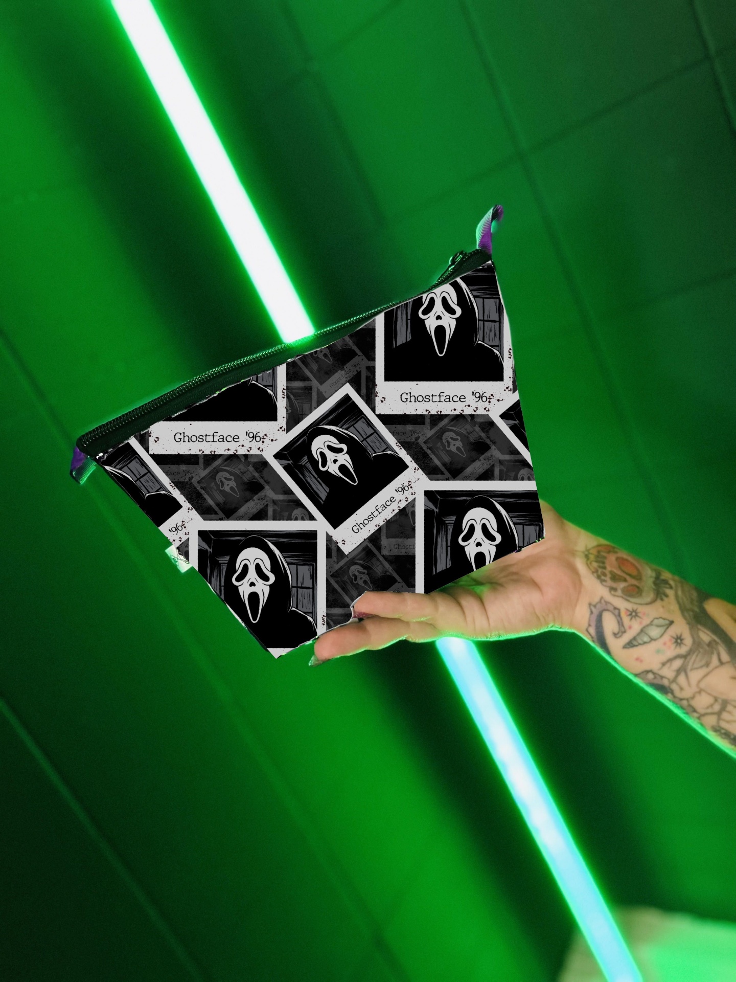 Necessaire preta com padrão Ghostface e texto 'Ghostface 96' e 'Scream' sendo segurada