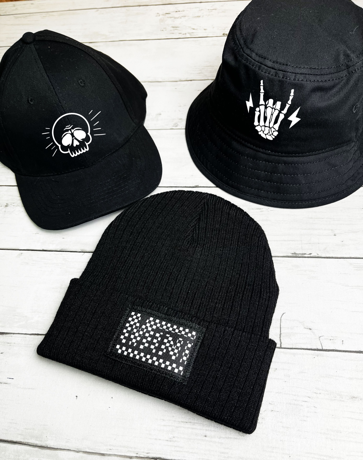 Boné preto com caveira branca, chapéu de pescador preto com mão esquelética branca, touca preta com emblema VAN.