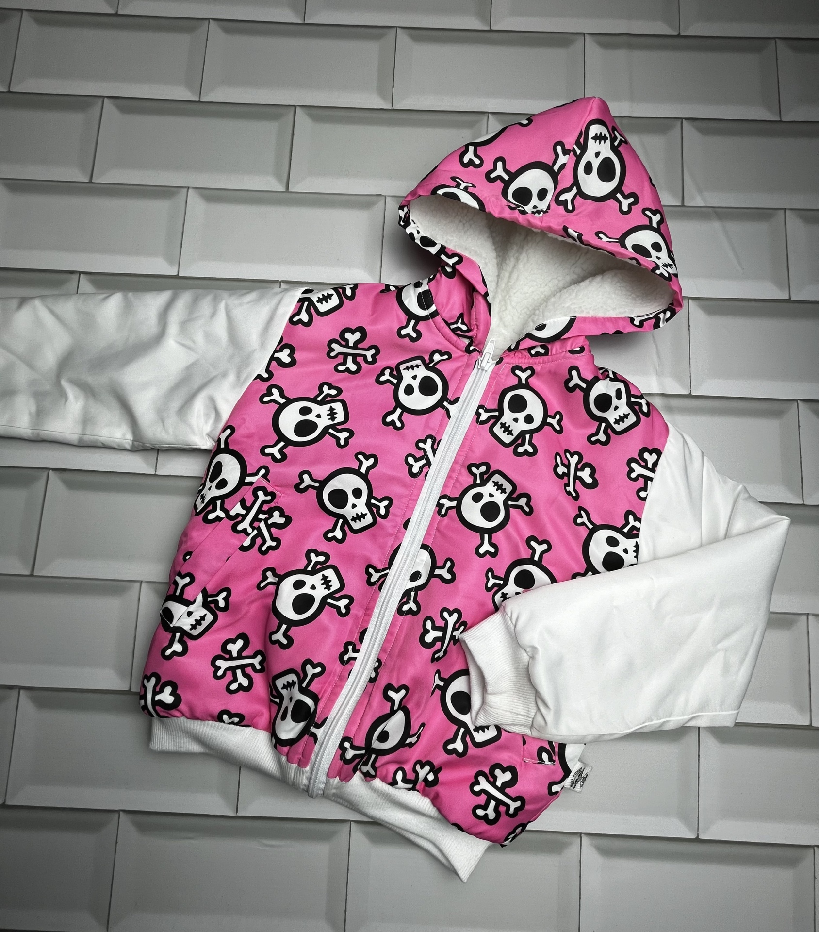 Casaco infantil rosa com caveiras e mangas brancas
