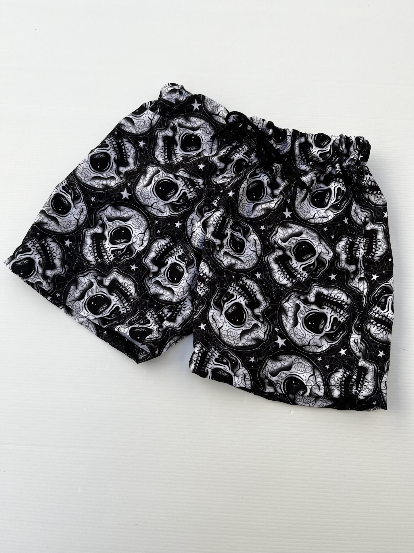 Calções pretos com padrão de caveiras brancas e cintura elástica