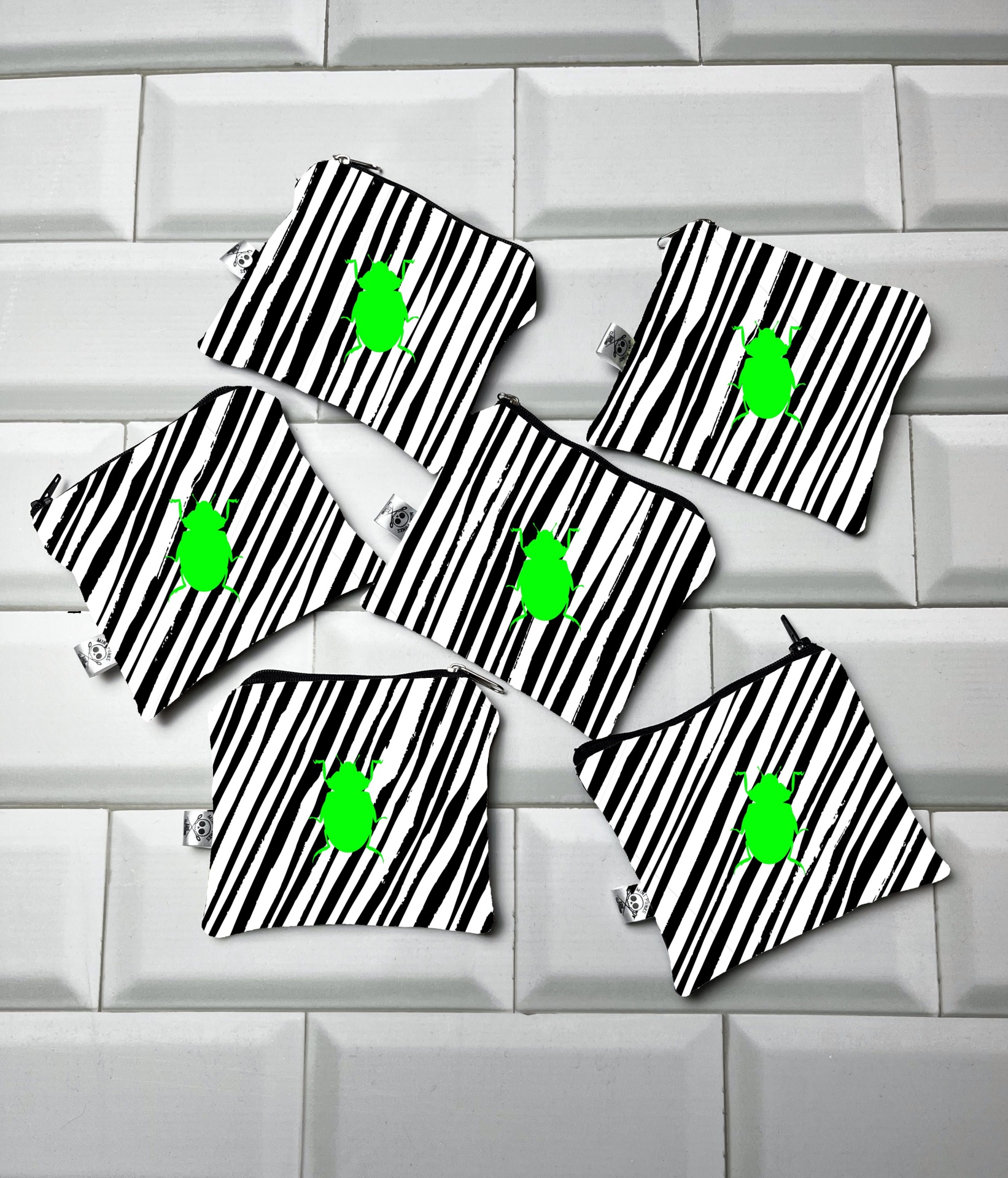 Seis pequenas bolsas de tecido listradas preto e branco com desenho verde no centro