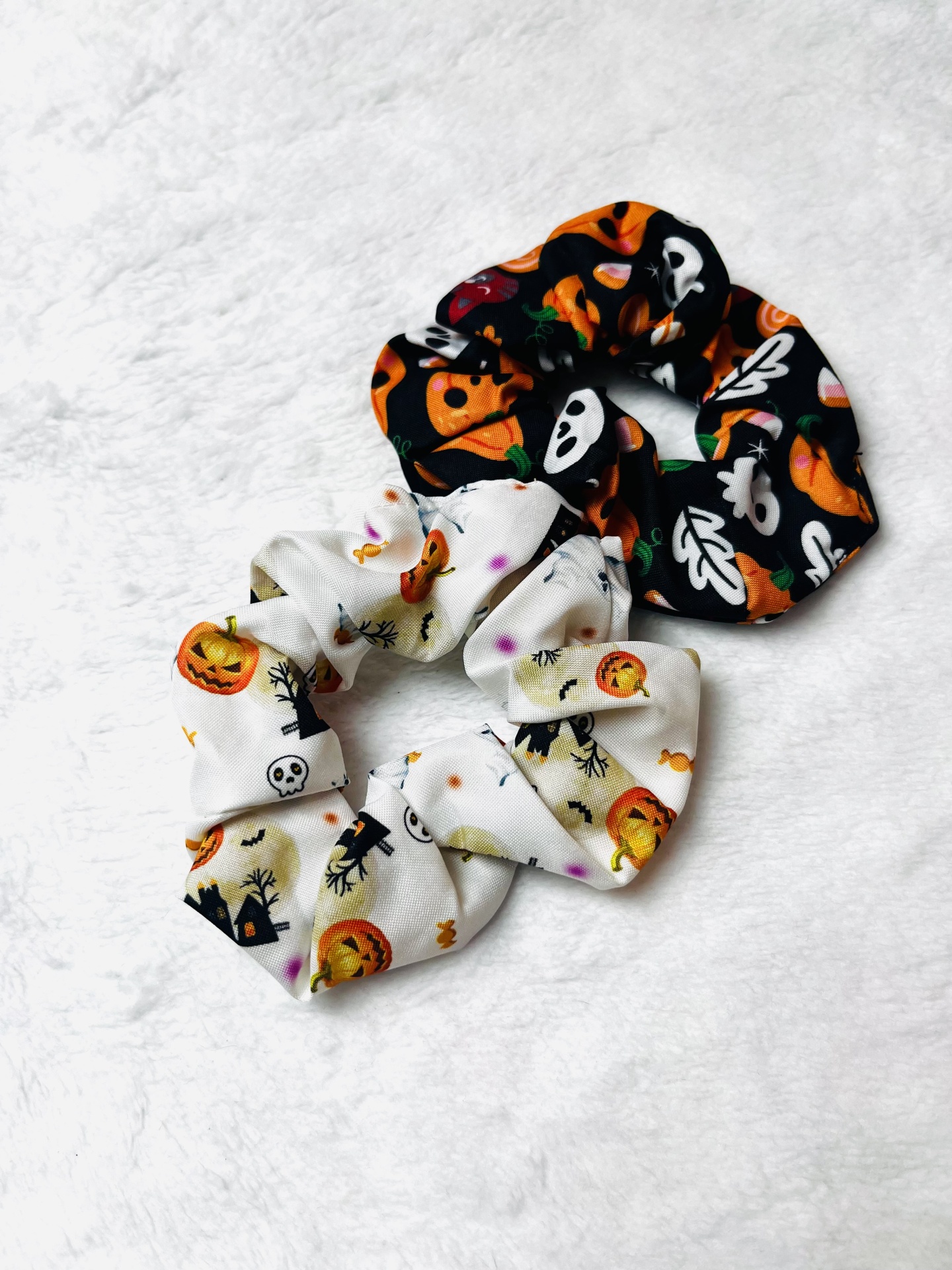 Dois scrunchies de Halloween com padrões coloridos sobre fundo branco
