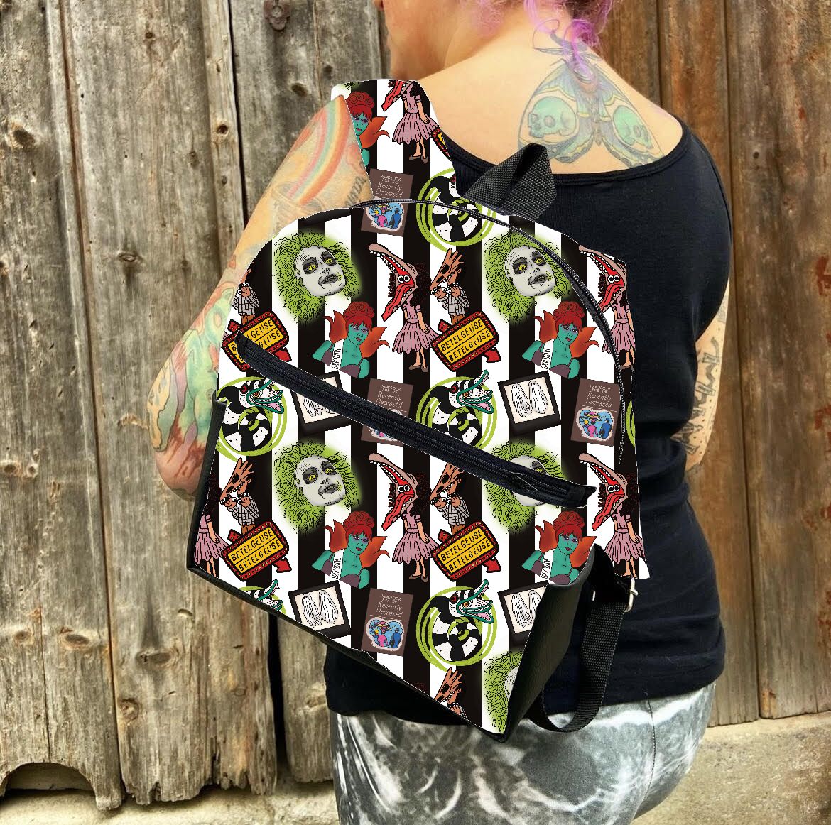 Mochila com padrão gráfico colorido e texto 'HORROR MOVIE' usada por pessoa com tatuagens